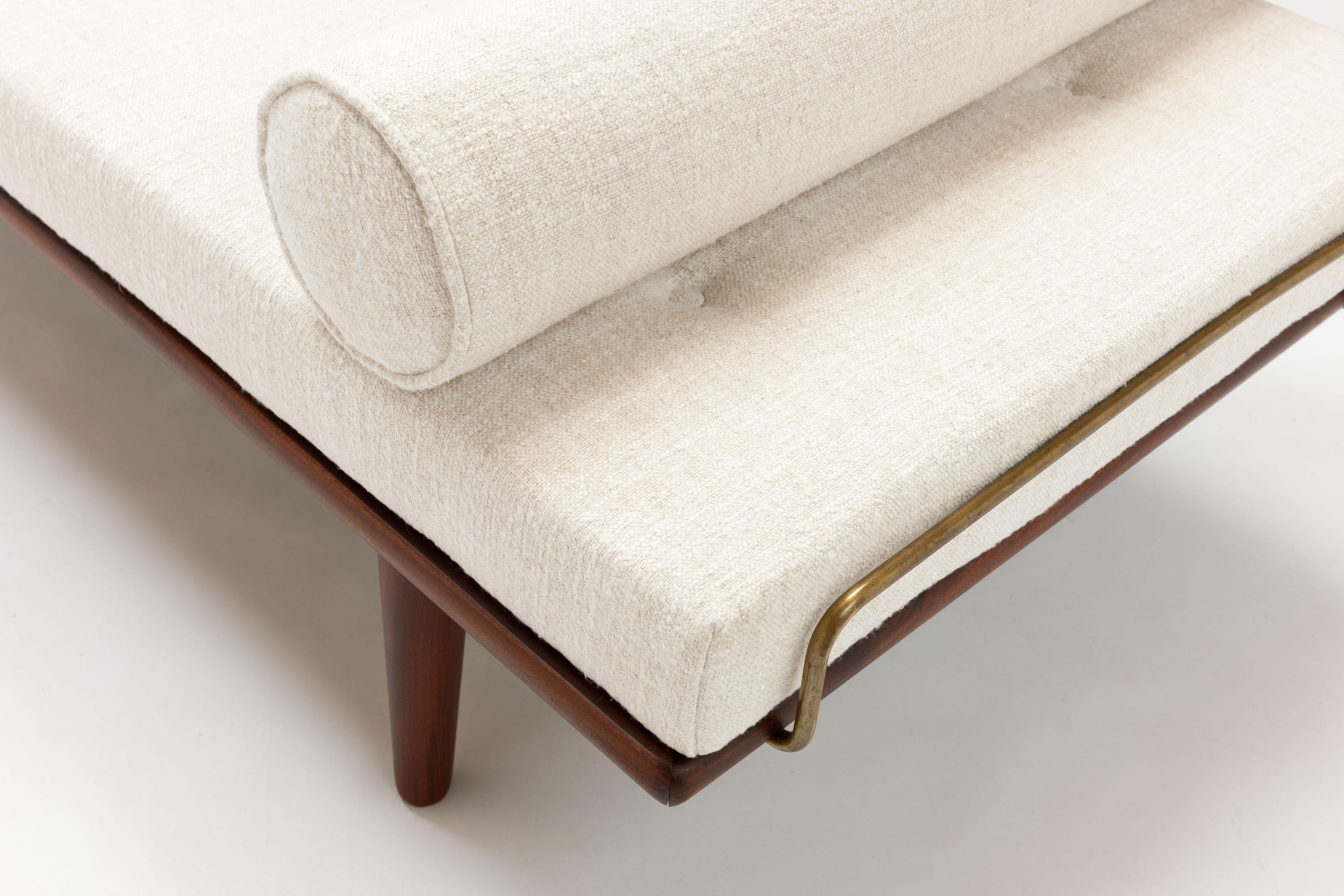 Daybed model GE19 from 1956 by Danish designer Hans J. Wegner constructed from solid teak with taper legs and beautiful brass mattress support bars on both sides. 
The daybed comes with a completely new buttoned mattress and neck roll pillow