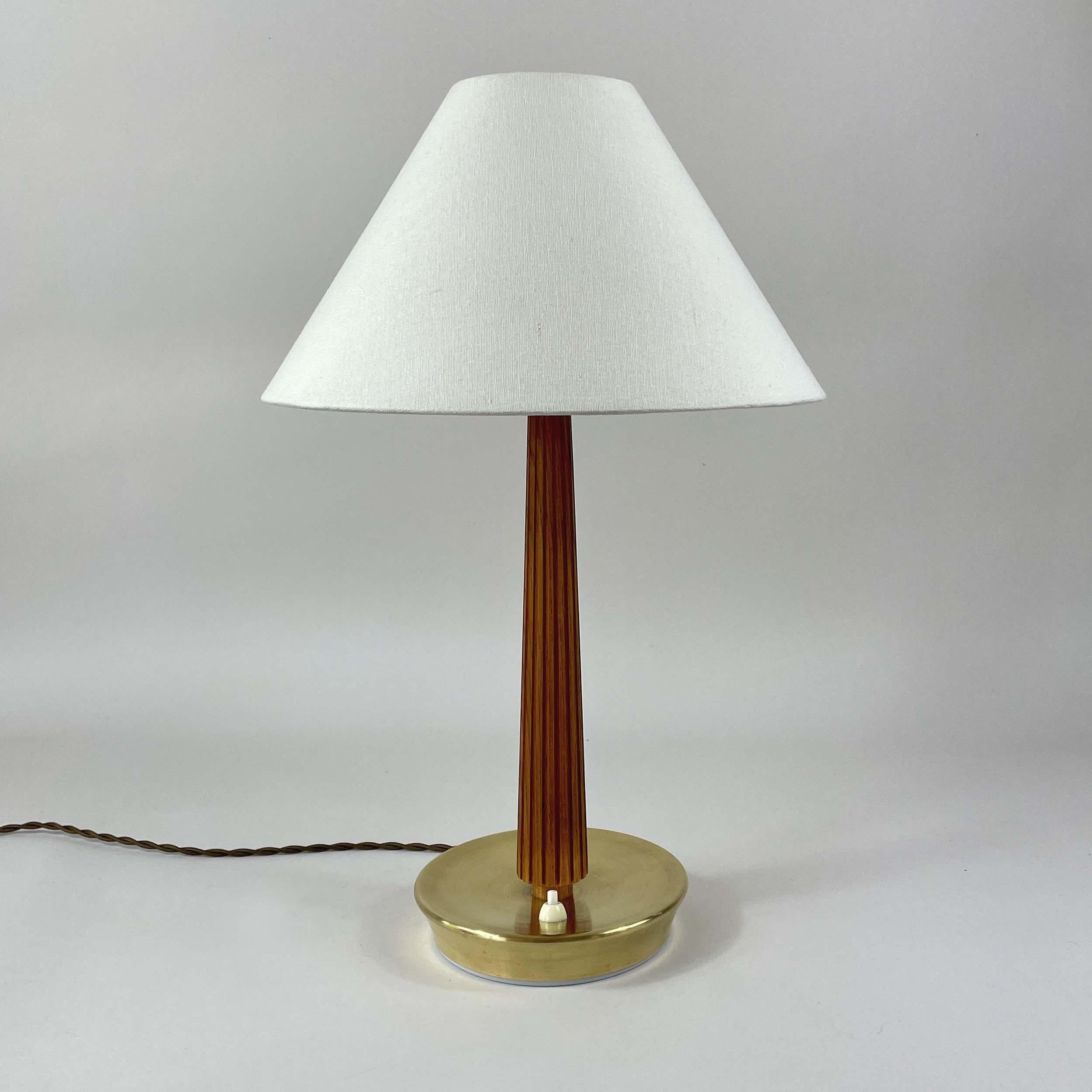 Cette lampe de table de style Art déco tardif a été conçue et fabriquée en Suède dans les années 1940 par ASEA (Allmänna Svenska Elektriska Aktiebolaget). 

Le luminaire présente un abat-jour conique en tissu blanc sur une haute colonne élancée avec
