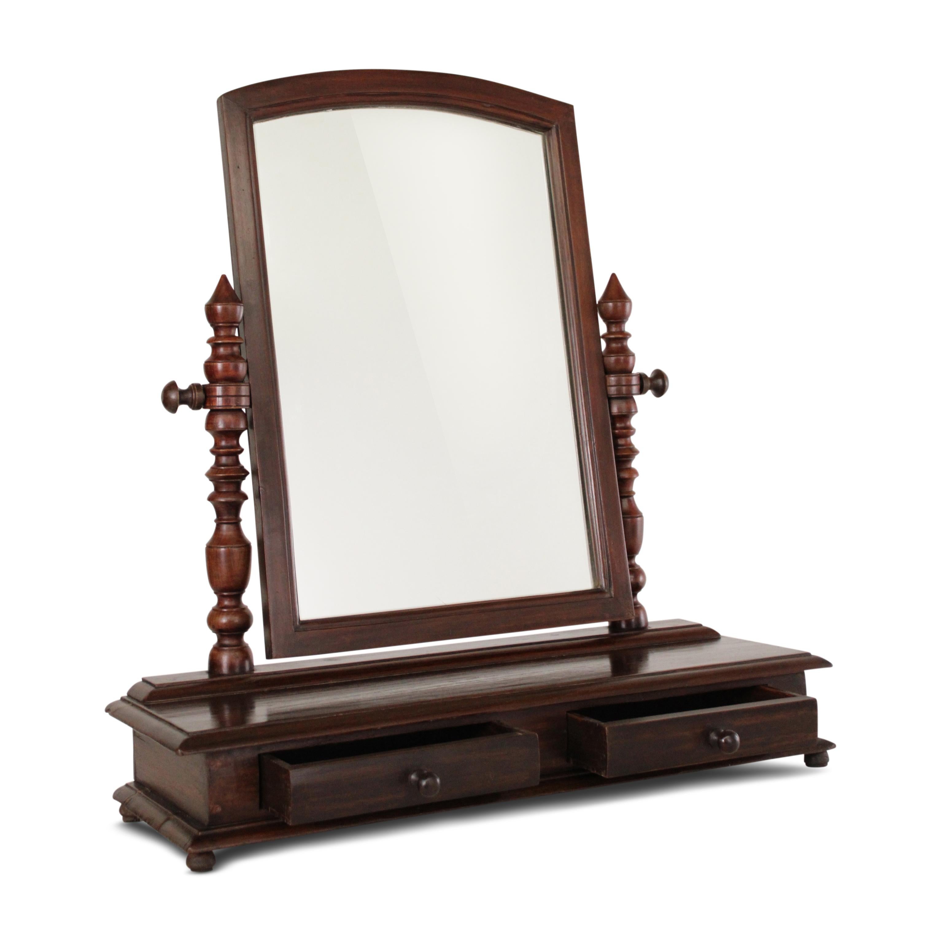 An elegant teak tabletop vanity mirror. The combination of the turned supports, original mirror frame, and drawer create a harmonious blend of form and function.