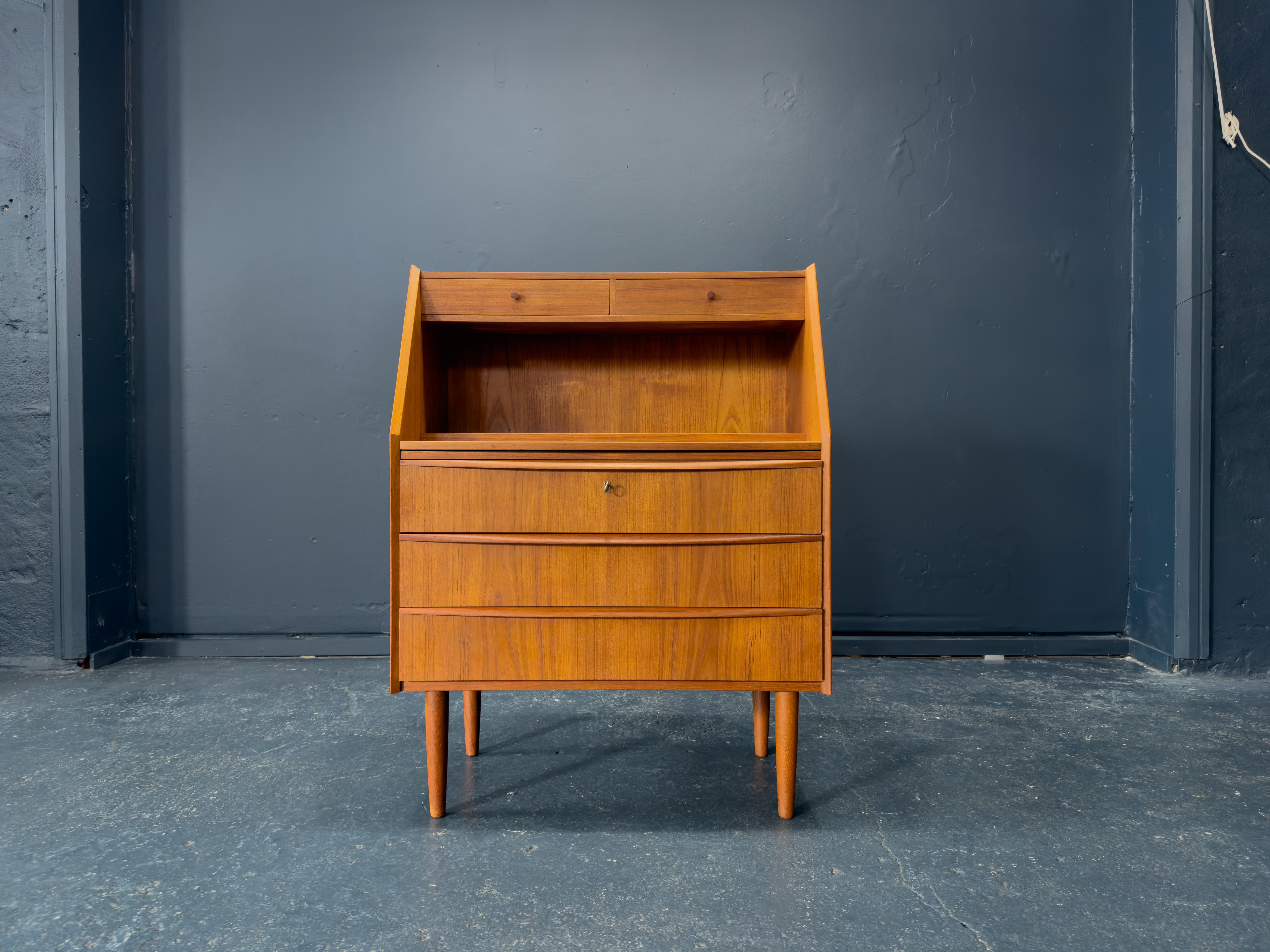 Made from a wonderfully warm teak wood this bureau is a gorgeous midcentury piece. With stunningly crafted design features, the piece boasts three large bottom drawers. Each drawer edge has been delicately carved, at an angle to function as seamless