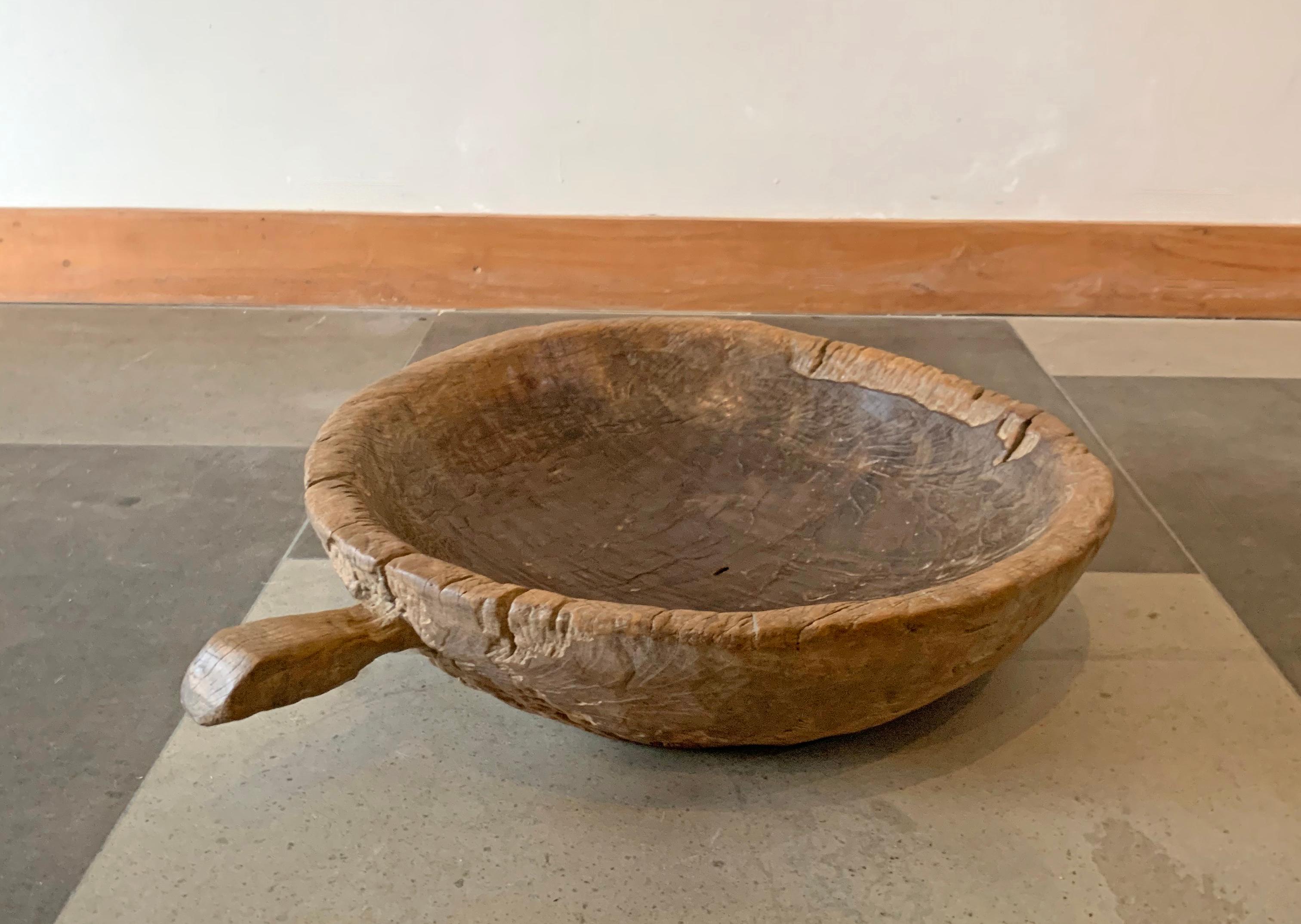 A teak burl wood bowl crafted on the island of Java, Indonesia. The bowl was cut from a much larger slab of burl wood and maintains an organic shape and natural texture. It has aged considerably over the decades contributing to its appeal.
