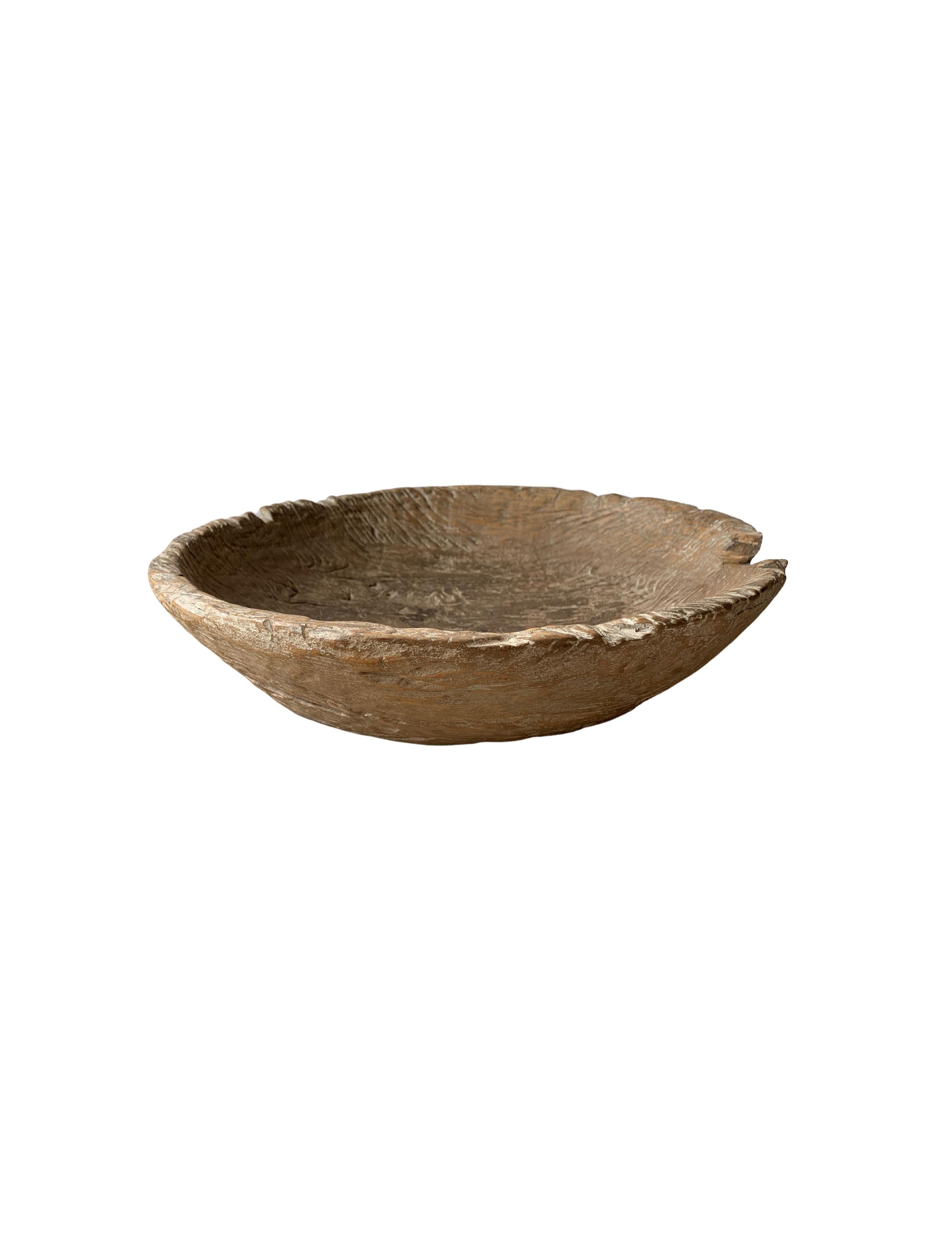 A teak burl wood bowl crafted on the island of Java, Indonesia. The bowl was cut from a much larger slab of burl wood and maintains an organic shape and natural texture. It has aged considerably over the decades contributing to its appeal. 

