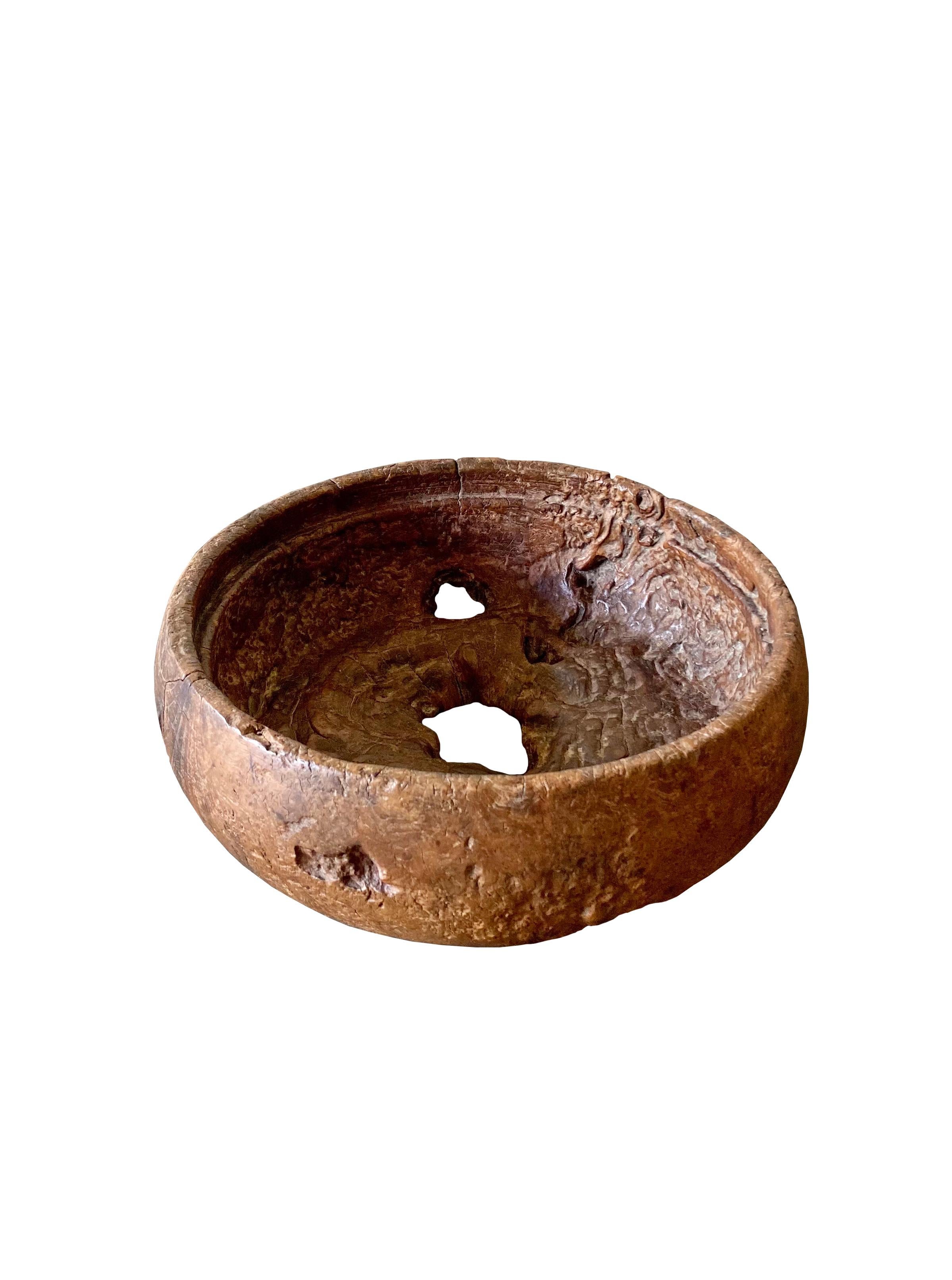 A teak burl wood bowl crafted on the island of Java, Indonesia. The bowl was cut from a much larger slab of burl wood and maintains an organic shape and natural texture. The multiple holes and indents contribute to its appeal. 

Dimensions: Height