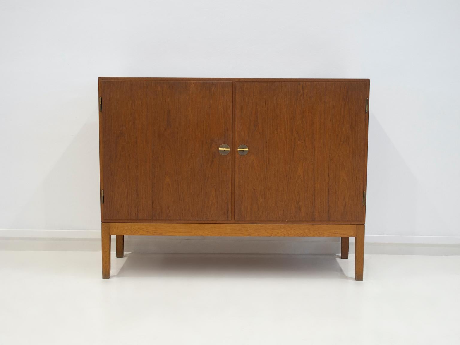 Børge Mogensen sideboard of teak with two doors in the front. Inside with shelves and pullout trays. Please note that the feet are not original and are made of oak. Brass keys that serve as handles are also added later. Manufactured by FDB møbler,