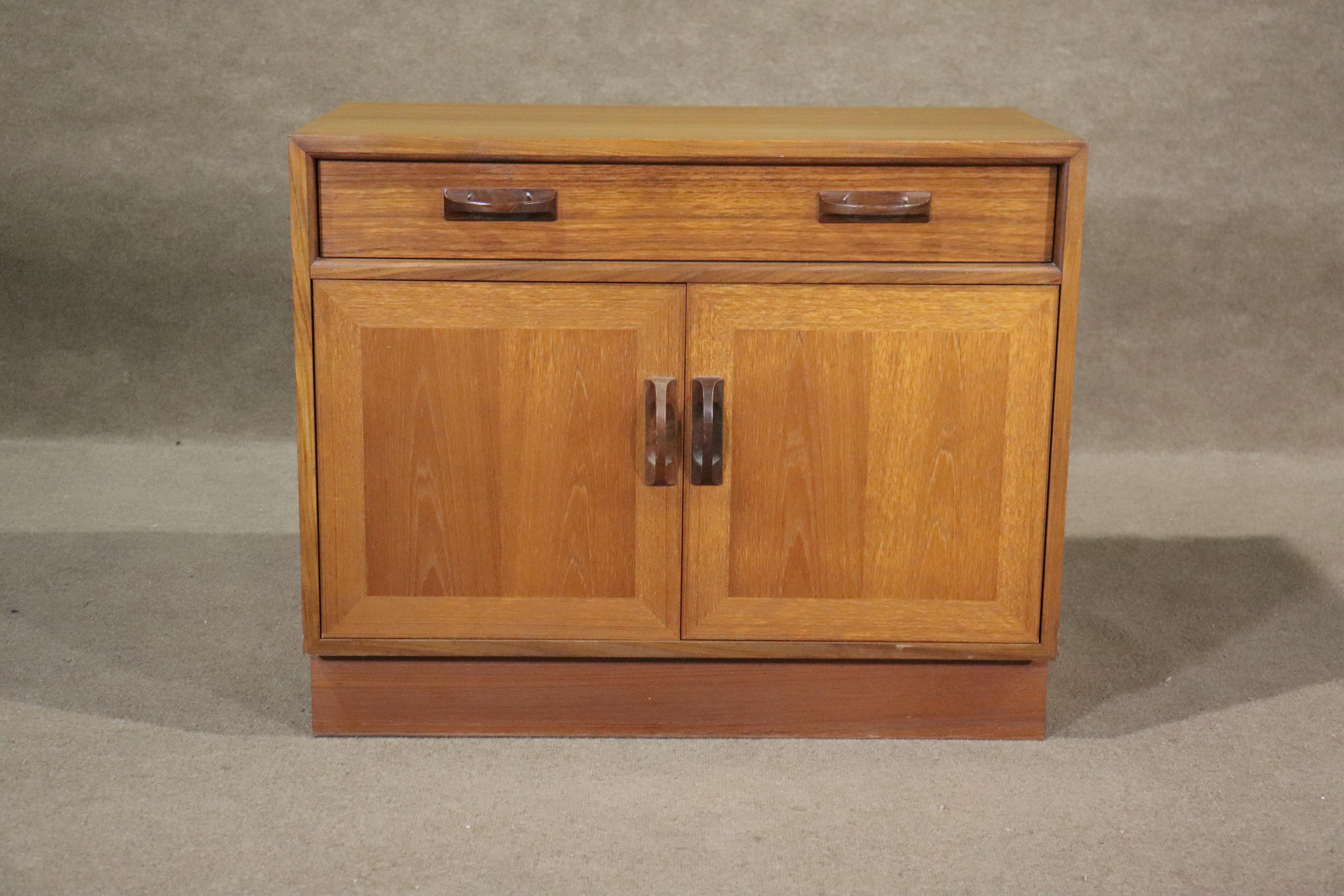 Fabriquée par G-Plan pour sa ligne 'Sierra', cette armoire vintage en teck est dotée d'un tiroir et de deux portes de rangement. Grain de bois teck sur toute la surface avec des poignées en teck foncé. Fabrication britannique et style