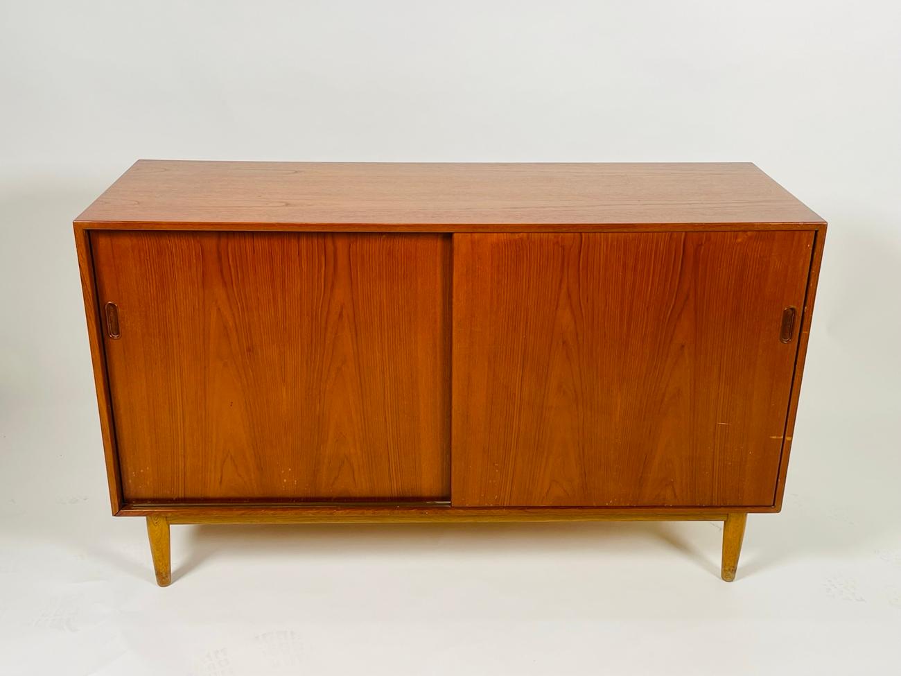 Beautiful cabinet made of teak. The cabinet has two sliding doors opening up to reveal 3 drawers on one side and 3 small drawers on the opposite side along with a shelf and two small cubbies.

The cabinet has a low profile, clean lines and would