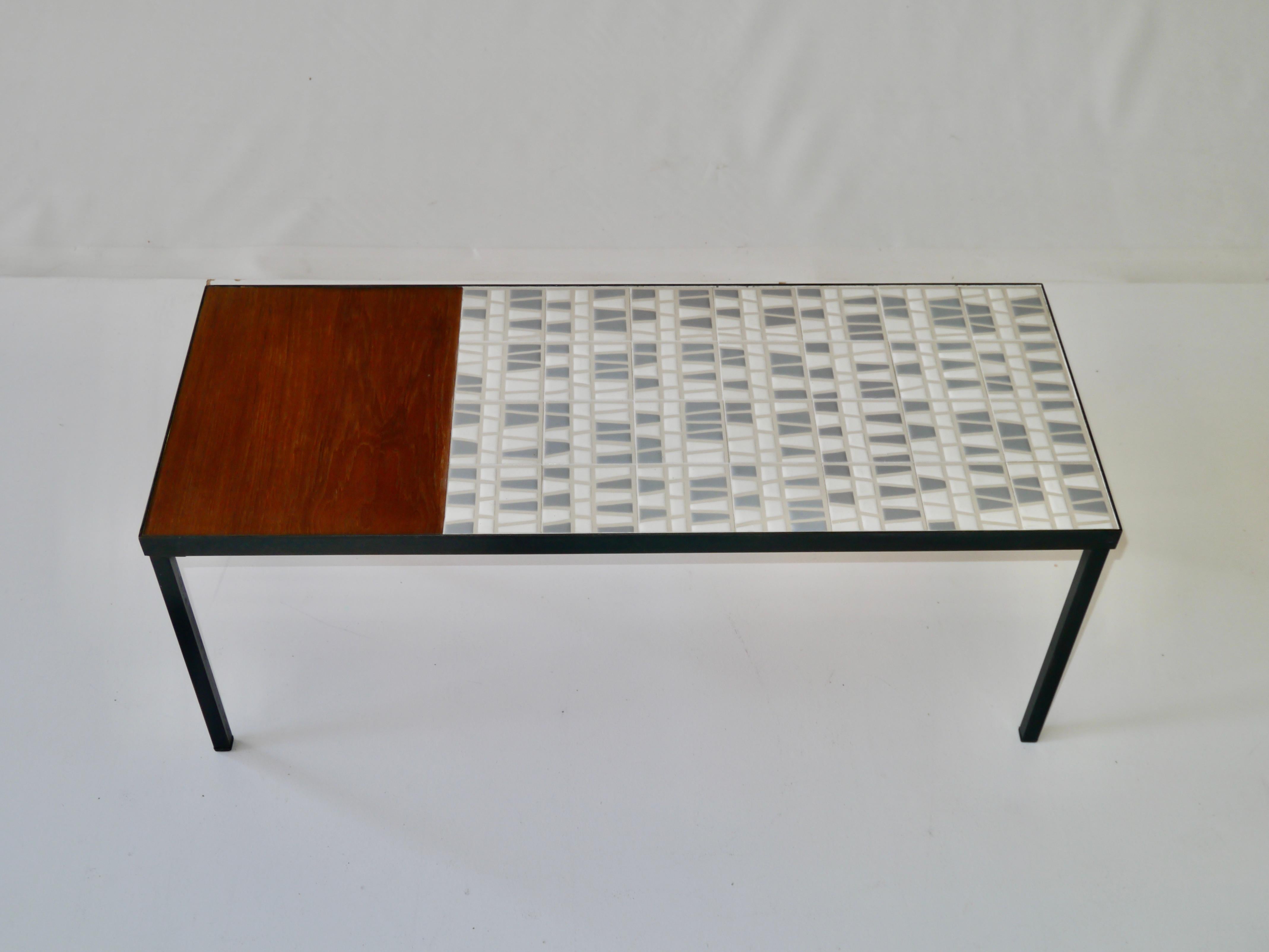 Coffee table made up of a glazed ceramic tiles top opposite a teak part,
structure and feet in black lacquered steel.
The handcrafted tiles are glazed using the paraffin reserve technique which brings particular relief to the design made with satin