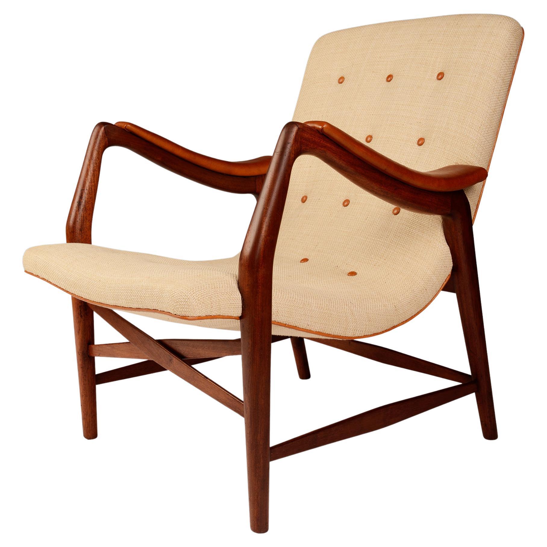 Teak chair with curvy seat upholstered with light fabric and leather details For Sale