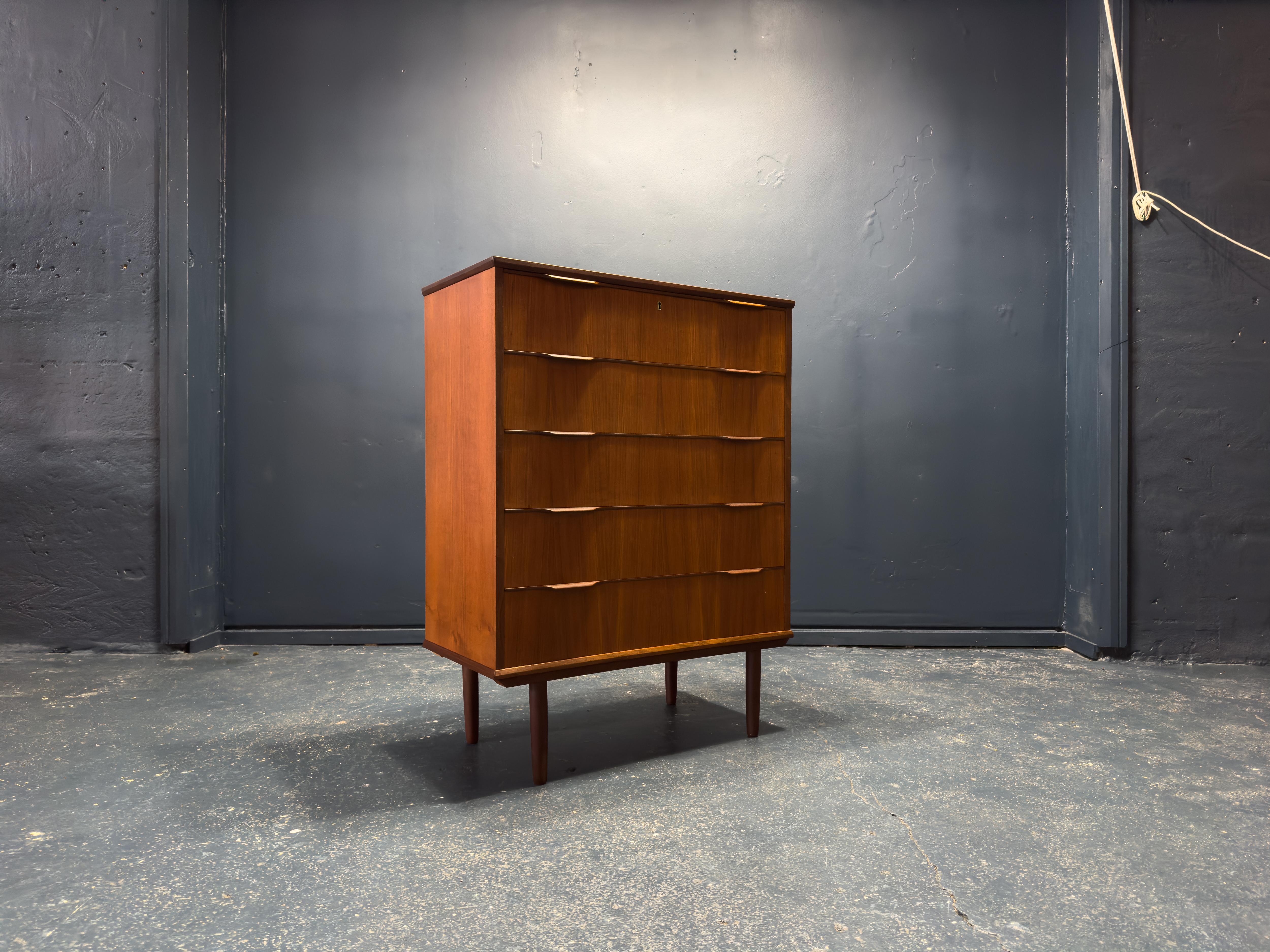 Questa cassettiera in teak di metà secolo è un pezzo di ottima fattura, costruito in teak ricco e dalle tonalità calde; le venature del legno sono sorprendenti, con variazioni naturali che ne esaltano la profondità e il carattere. Il design elegante