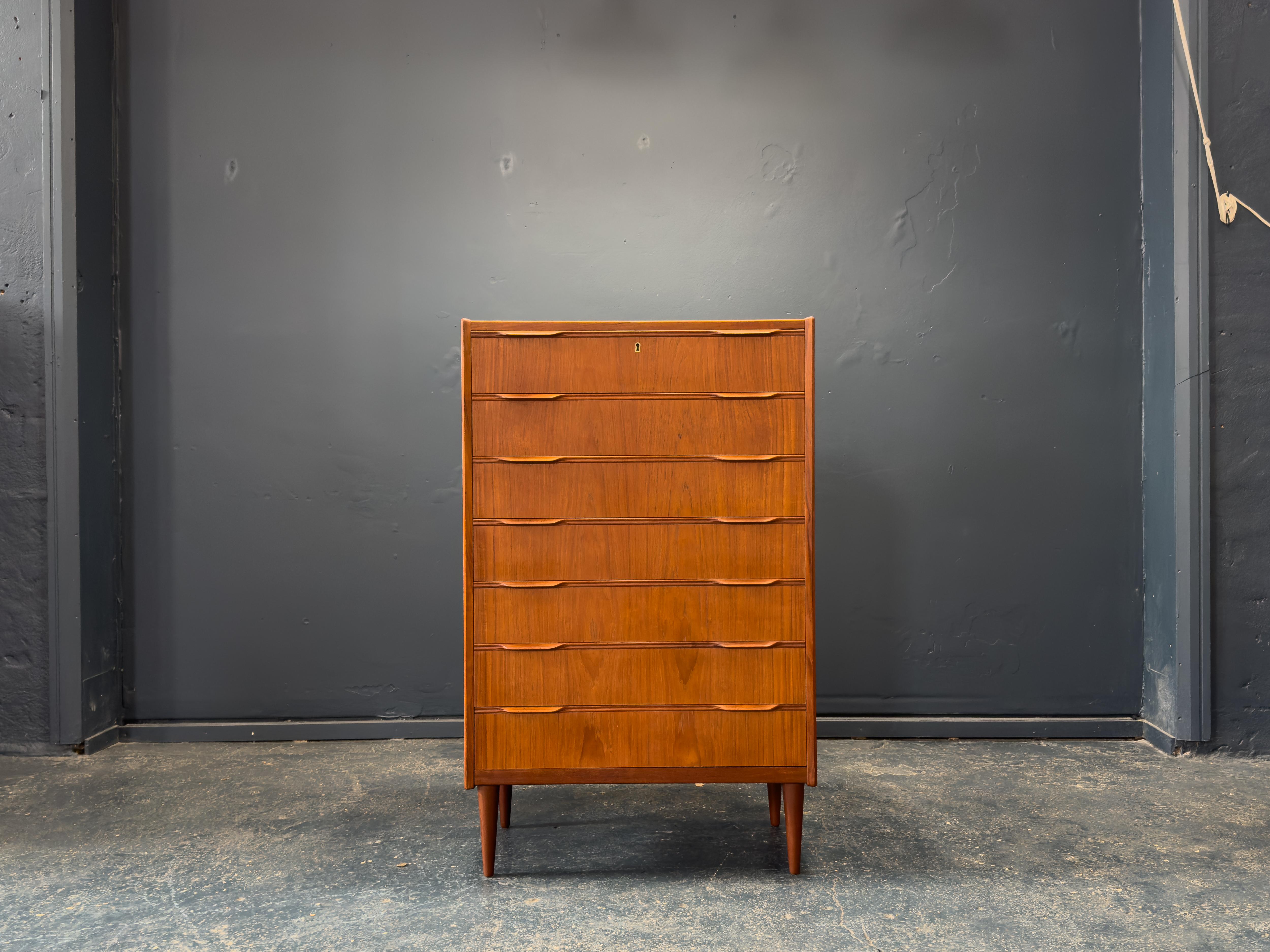 Diese elegante Kommode aus Teakholz ist ein Beispiel für raffiniertes dänisches Design, bei dem Form und Funktionalität im Vordergrund stehen. Mit seinem hohen, schmalen Profil bietet das Möbelstück großzügigen Stauraum mit acht sanft abgestuften