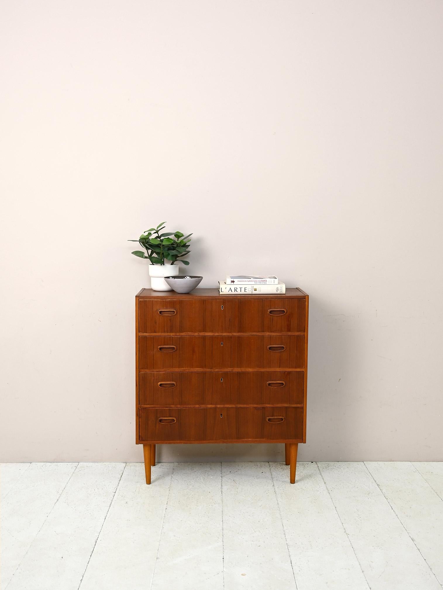 Scandinavian vintage 1960s chest of drawers.

A piece of furniture with clean, essential lines. The squared structure is enhanced by the carved wooden handle of the drawers and the conical legs.
Thanks to the ability to close all the drawers, it can
