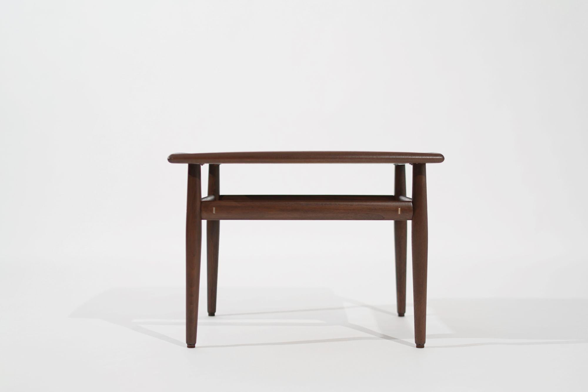 Indulge in the enduring charm of mid-century modern design with our meticulously restored Teak Coffee/End Table, a 1950s masterpiece by Danish designer Grete Jalk for Mobelfabrik, immaculately revived by Stamford Modern. Crafted with precision, this