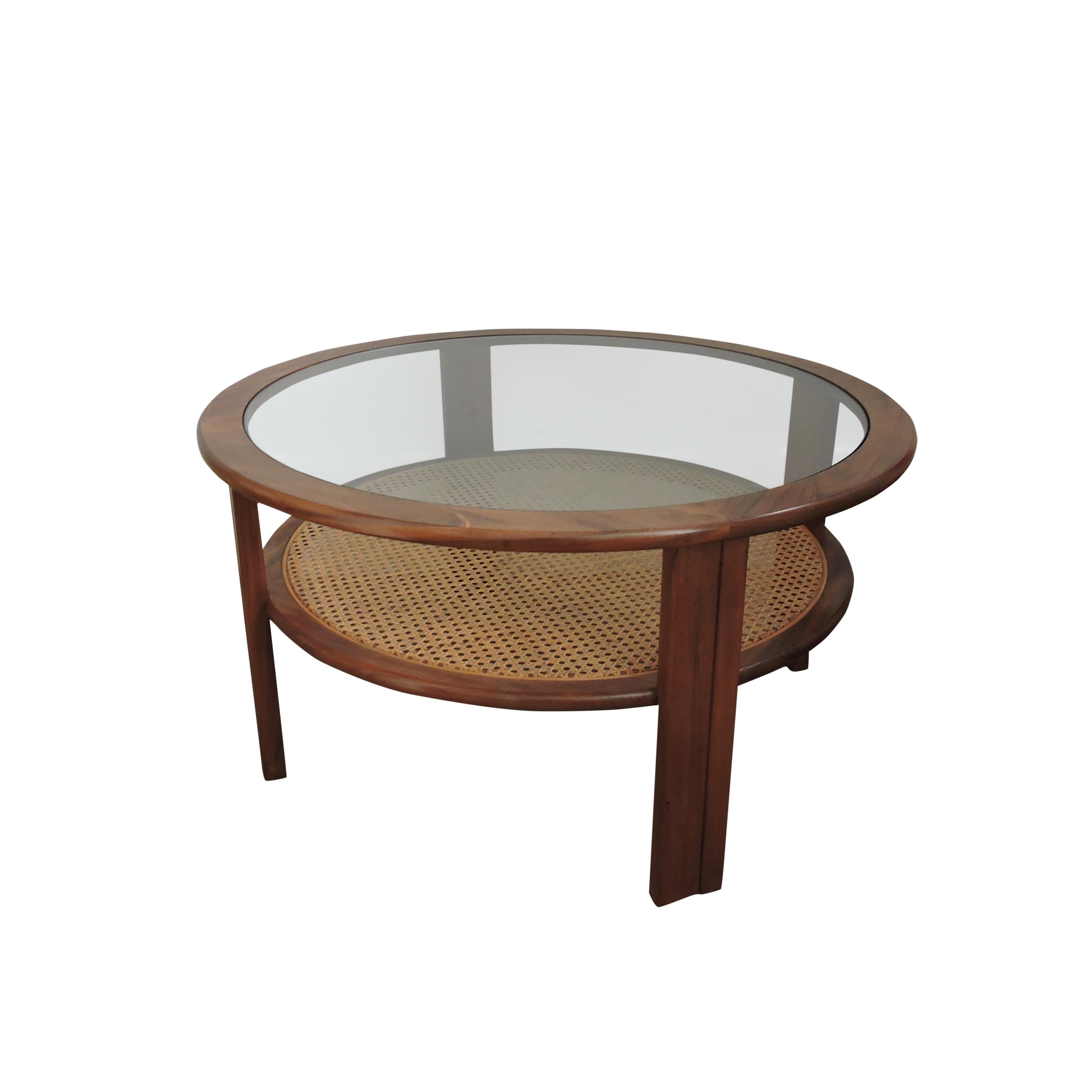 A circular glass topped teak coffee table by G-Plan with a lower cane shelf.