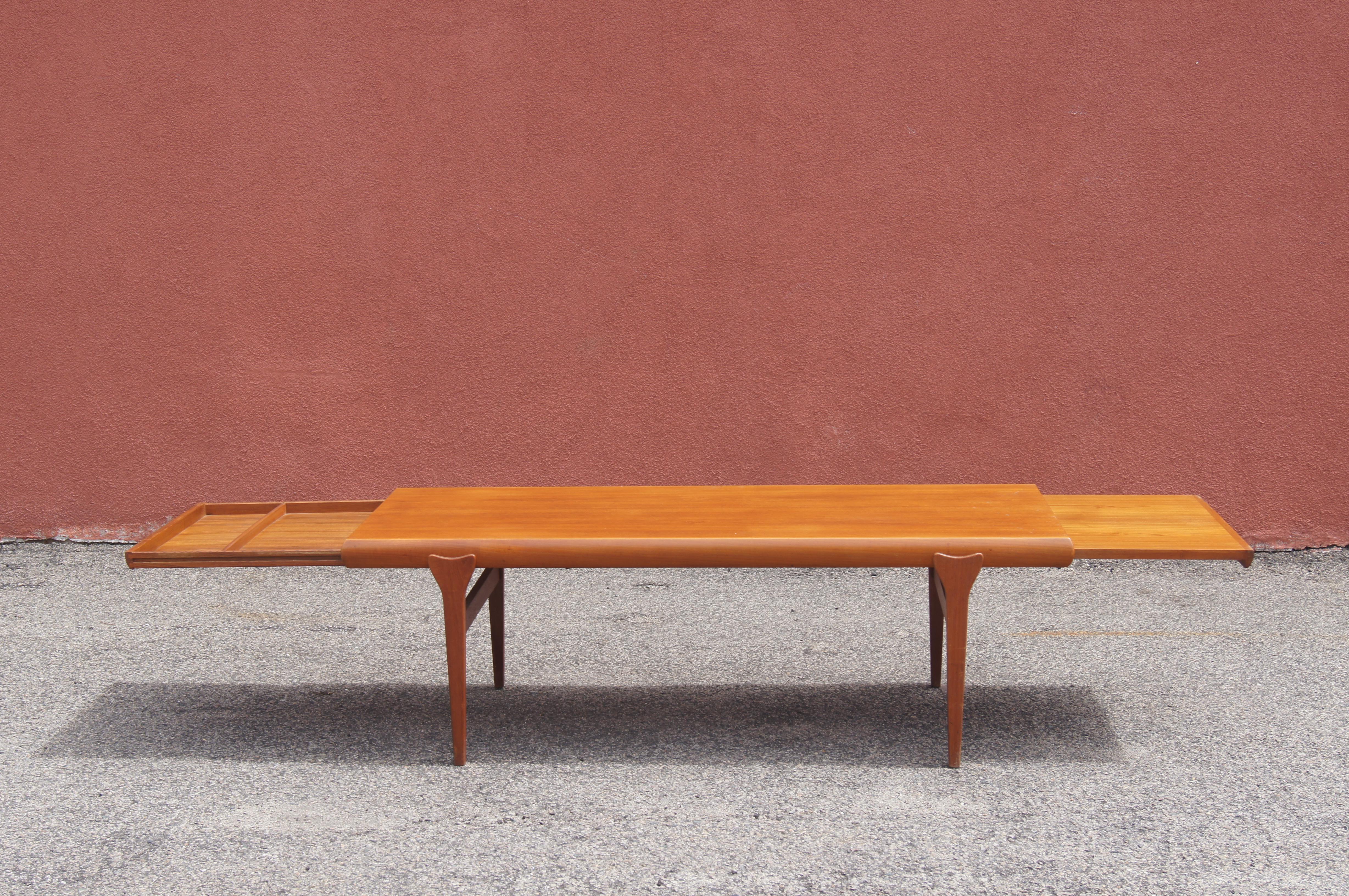Johannes Andersen designed this mid-century teak coffee table for Uldum Møbelfabrik. Sitting on striking tapered legs, the rectangular teak top has rounded edges that conceal integrated extensions on either side: one 19-inch pullout serves as a