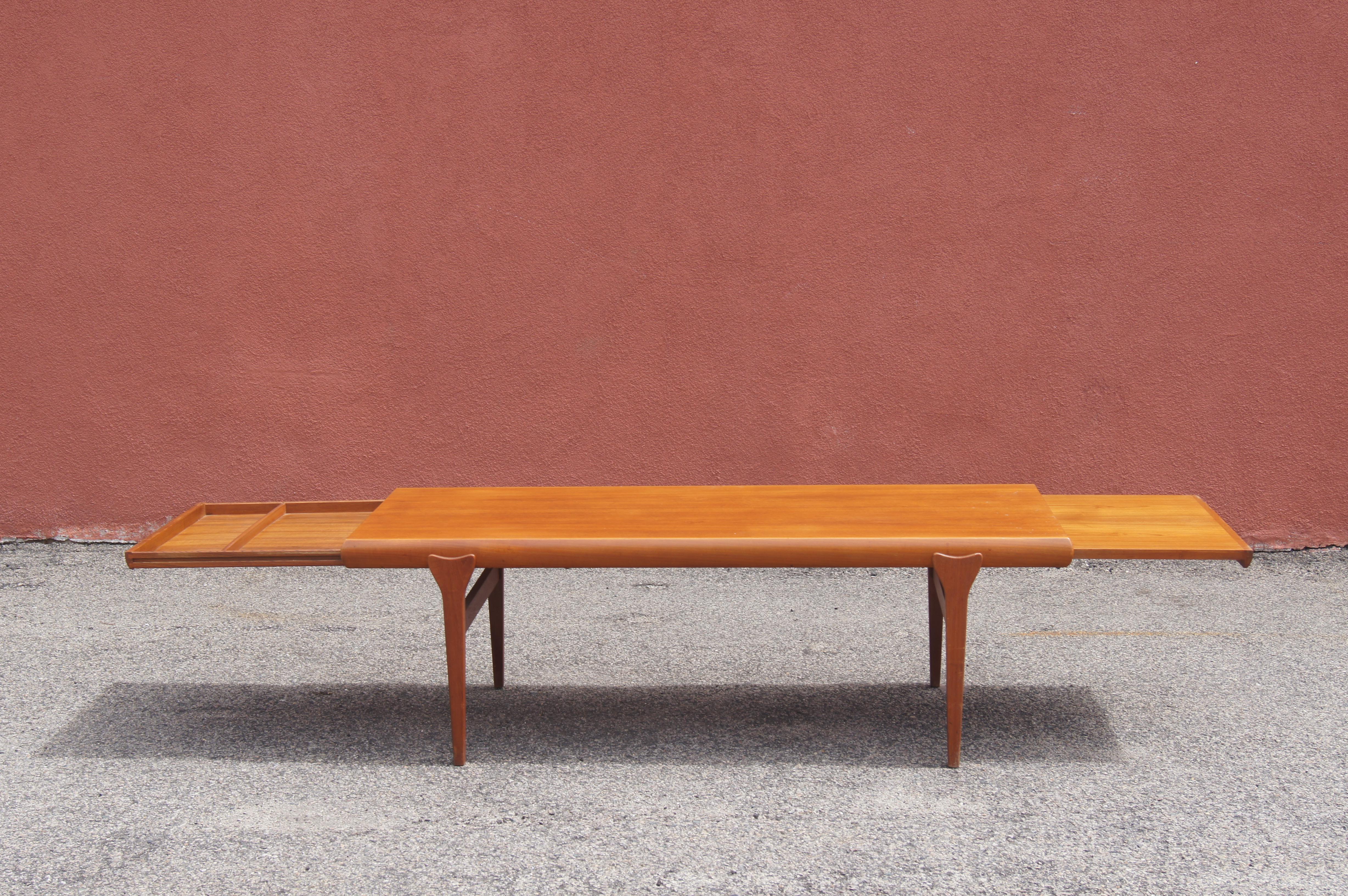 Johannes Andersen ha progettato questo tavolino in teak di metà secolo per Uldum Møbelfabrik. Il piano rettangolare in teak, che poggia su gambe affusolate, ha bordi arrotondati che nascondono estensioni integrate su entrambi i lati: un cassetto da