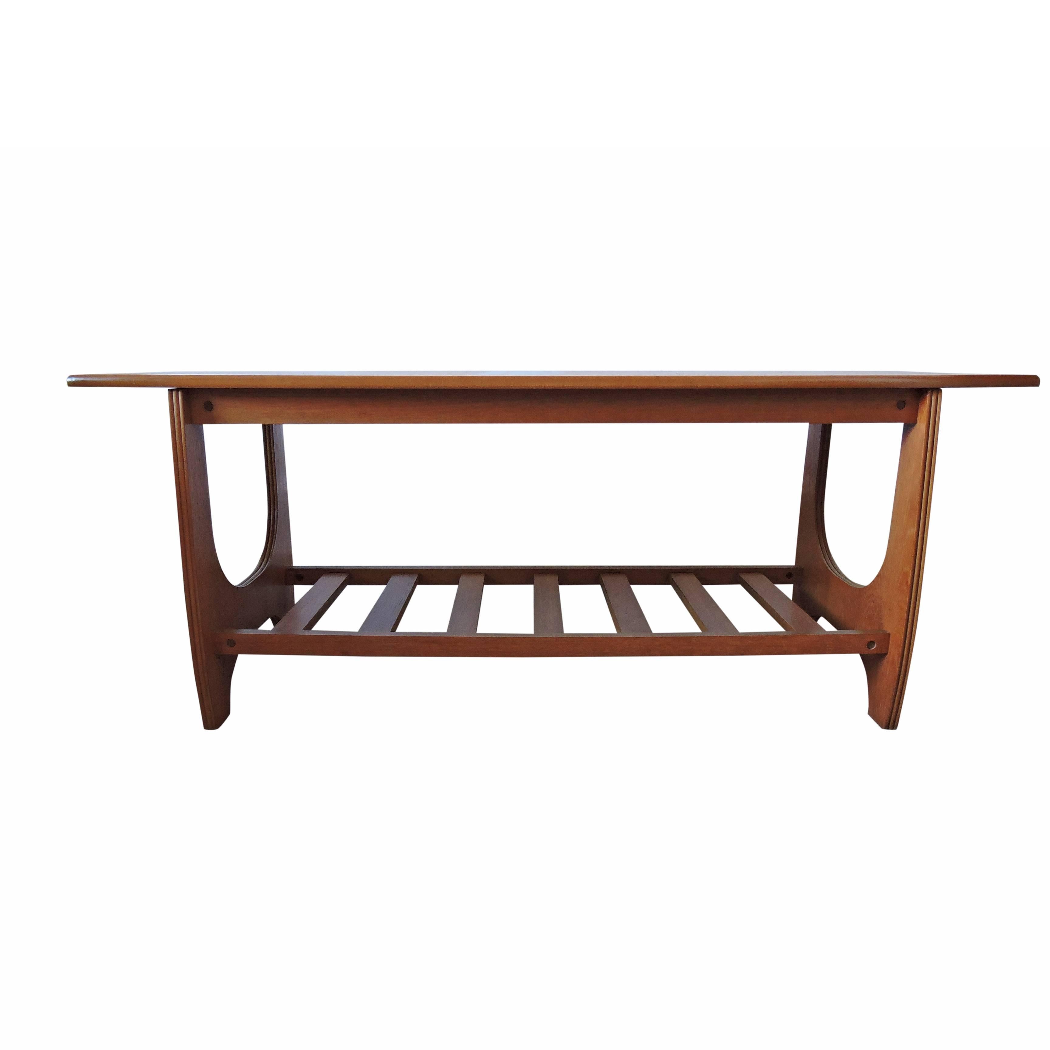 This 1960s coffee table features a top with a teak finish, as well as a slatted magazine rack.