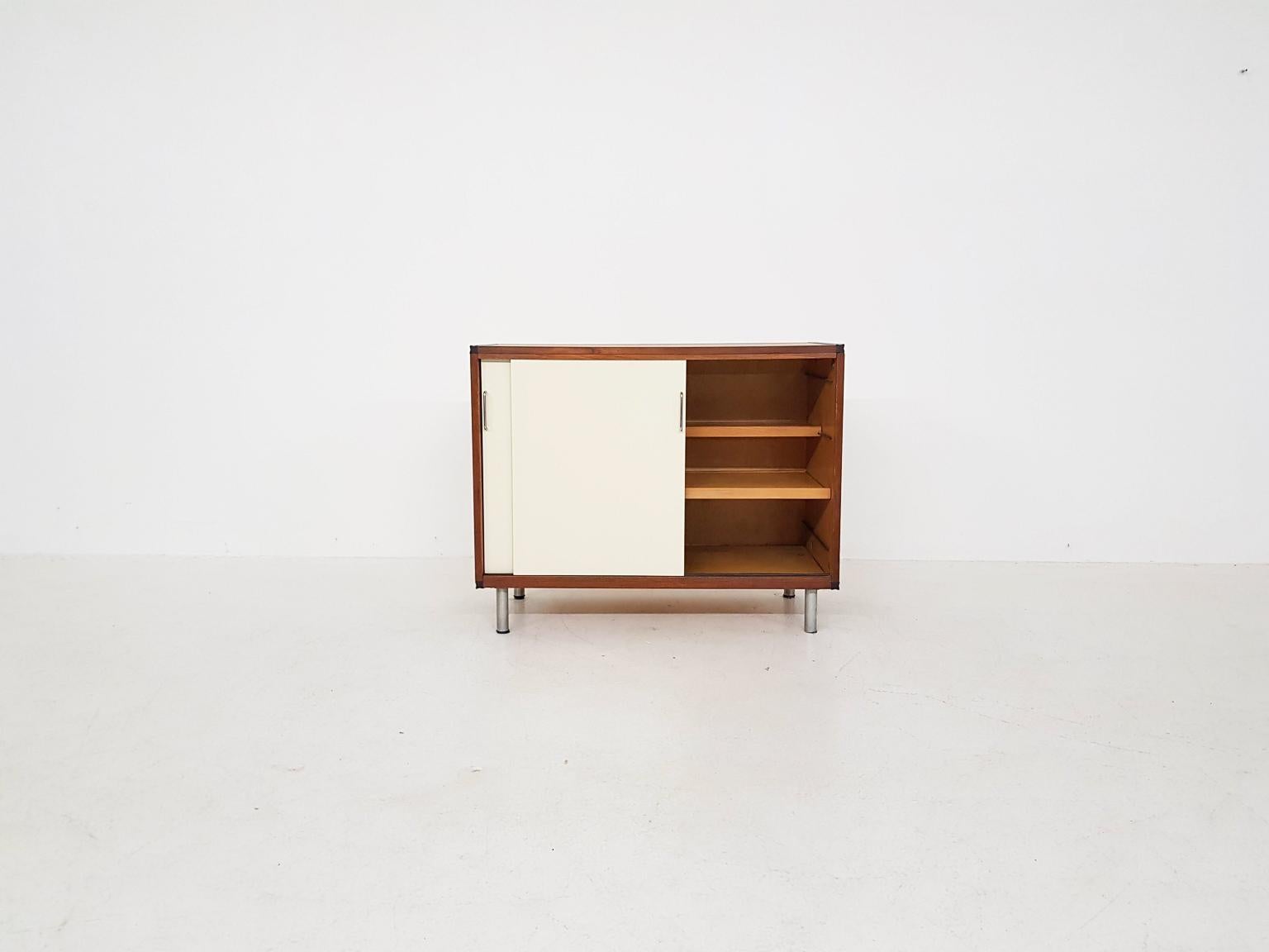 Small teak credenza with white sliding doors by Dutch designer Cees Braakman for U.M.S. Pastoe, made in the Netherlands in the 1960s.

This credenza is part of the 