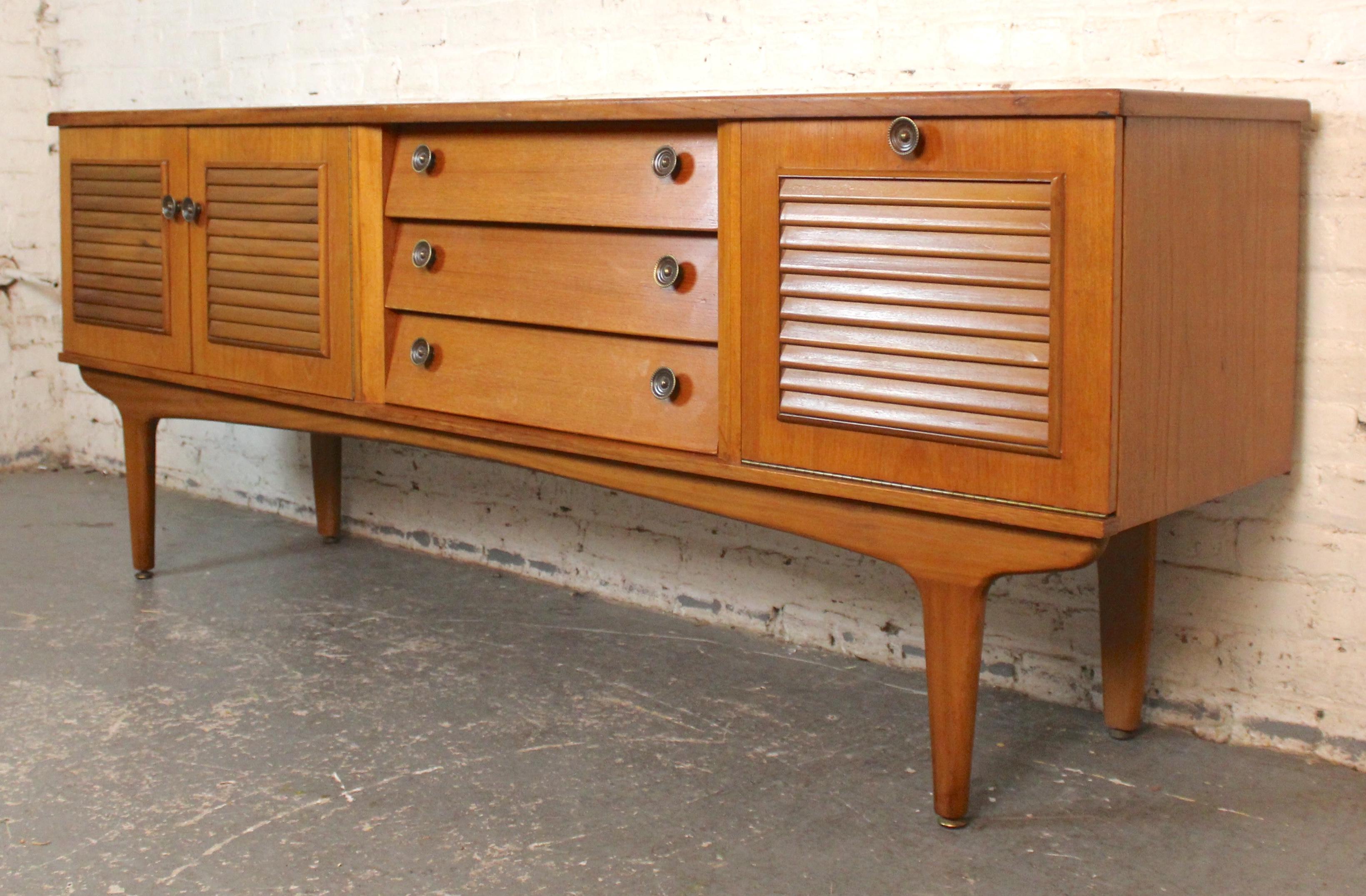 Questa credenza dal profilo basso presenta un design a feritoie su tutta la parte frontale. I cassetti centrali sono inclinati per dare maggiore definizione, mentre le ante laterali sono caratterizzate da un design a doghe. Perfetto per riporre i