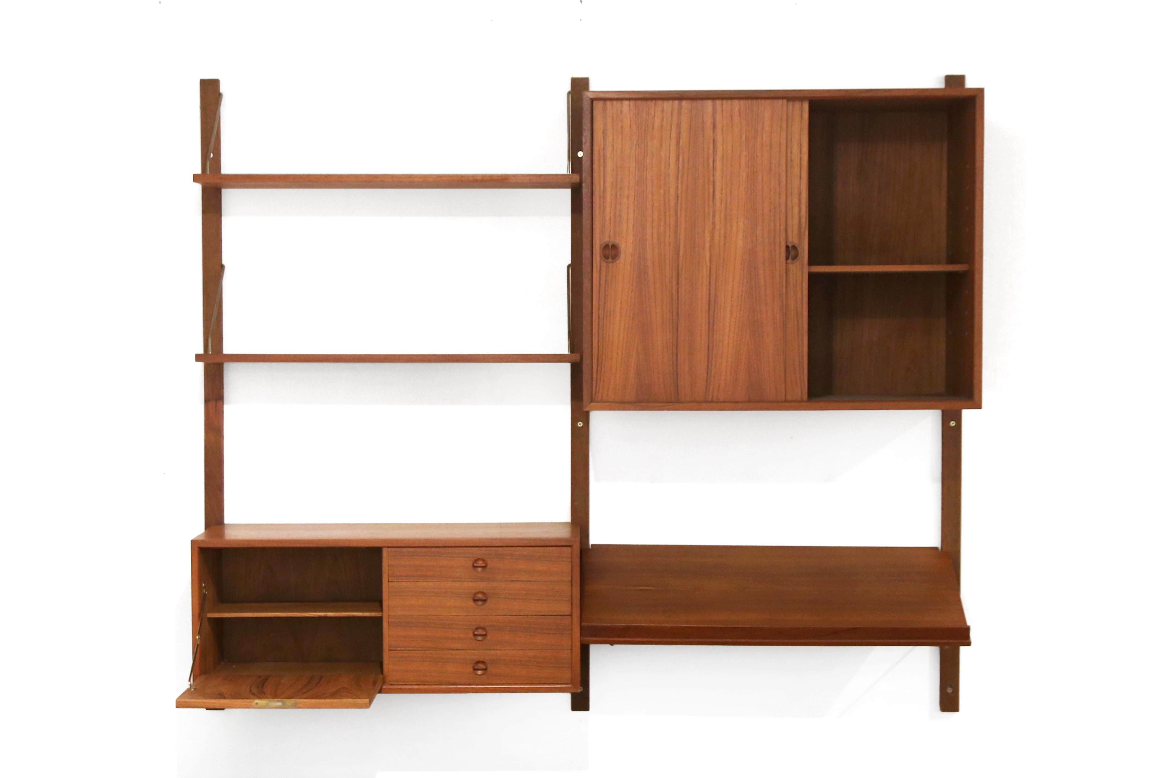 Beautiful vintage modular Danish wall cabinet in the style of Poul Cadovius. The cabinet has 3 wooden uprights, 2 shelves of 30 cm, a magazine shelf, a large cabinet with sliding doors and a cabinet with 4 drawers and a flap. The system is made of