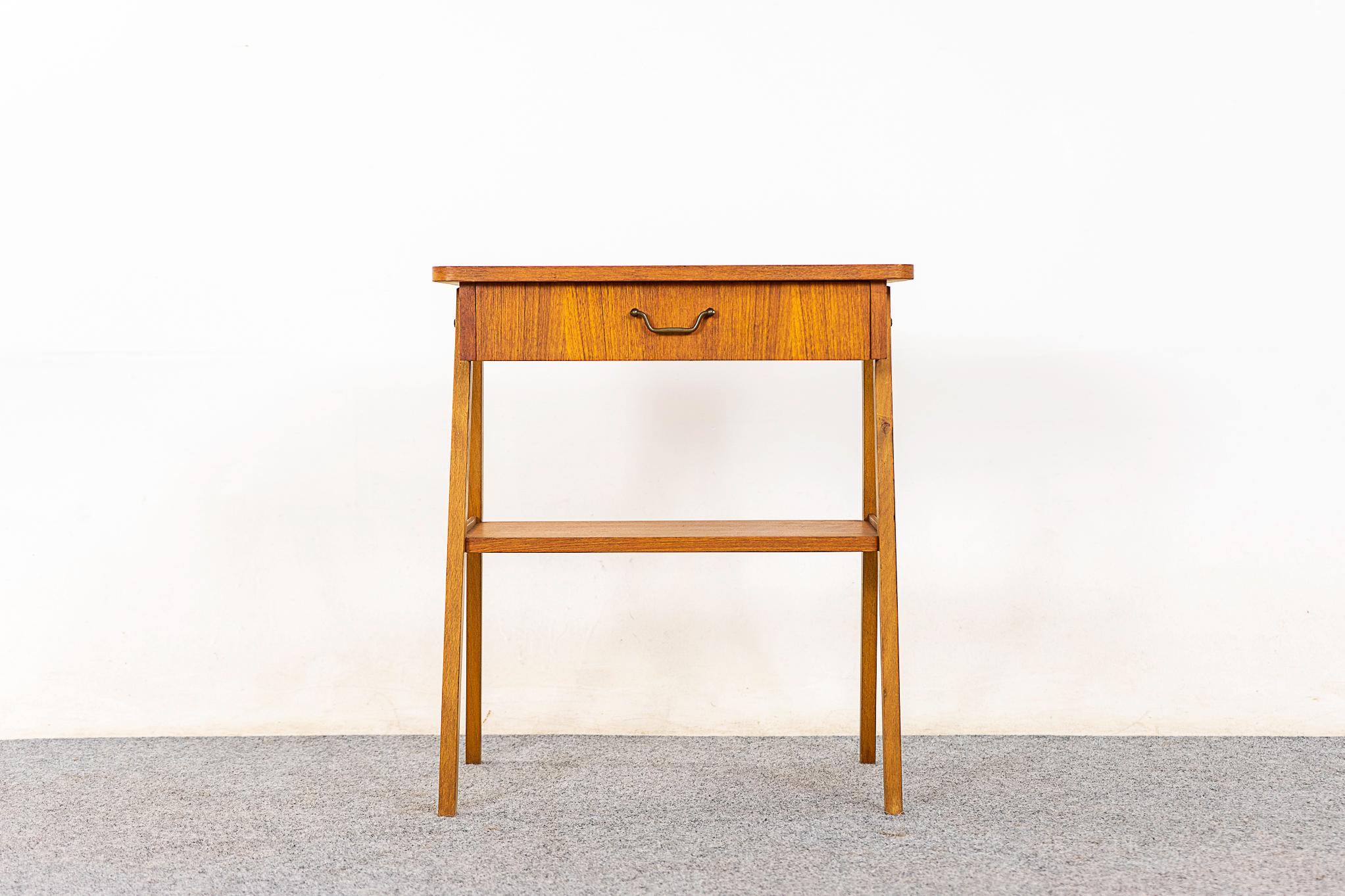 Teak bedside table, circa 1960's. Veneered case with slender splayed legs with metal accents. Sleek drawer with a lovely metal finger pull and handy lower shelf!

Please inquire for remote and internationals shipping rates.