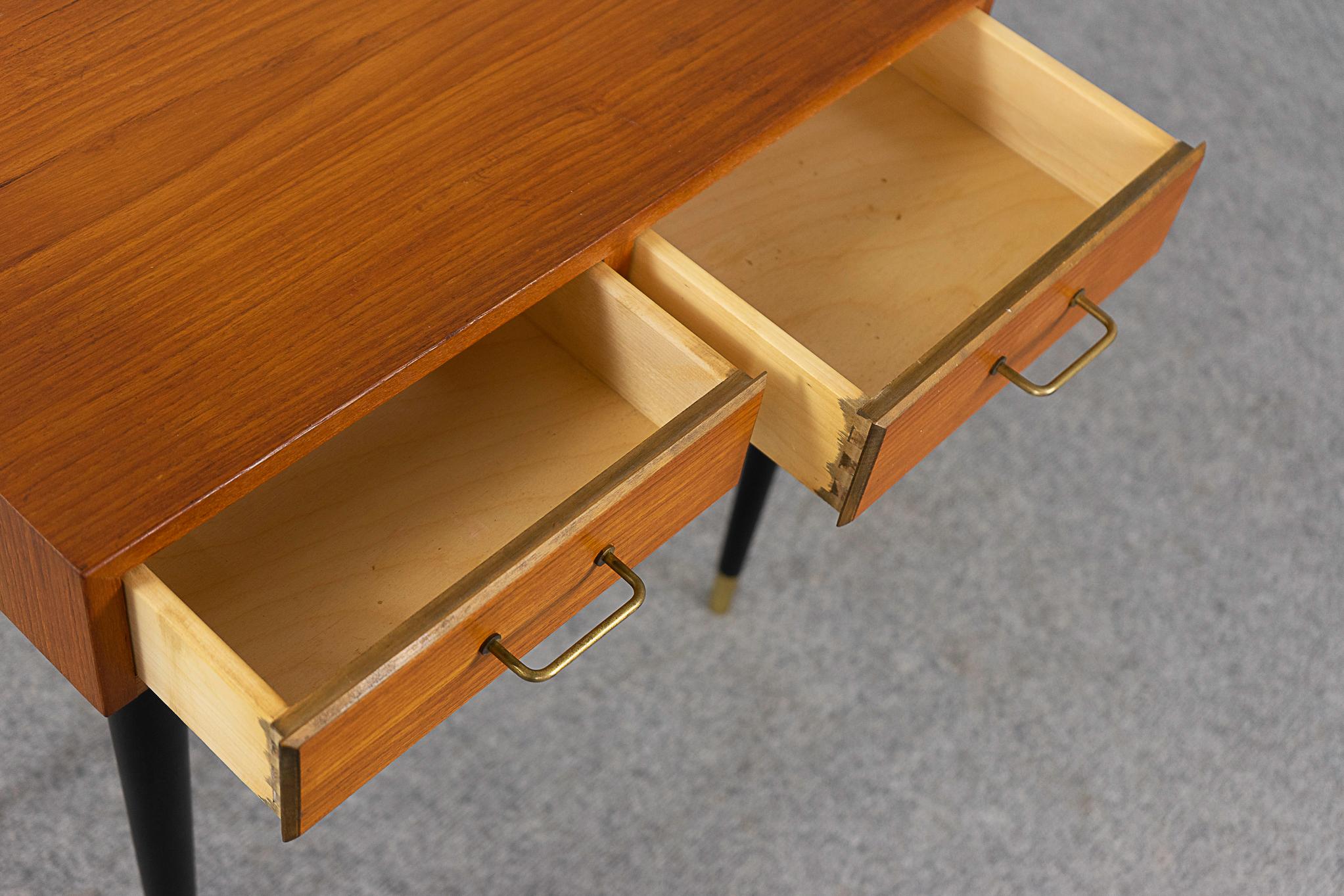 Teak mid-century bedside table, circa 1960's. Slender contrasting legs, dovetail drawers with metal pulls, beautifully veneered case. One metal foot cap missing. 

Please inquire for remote and international shipping rates.