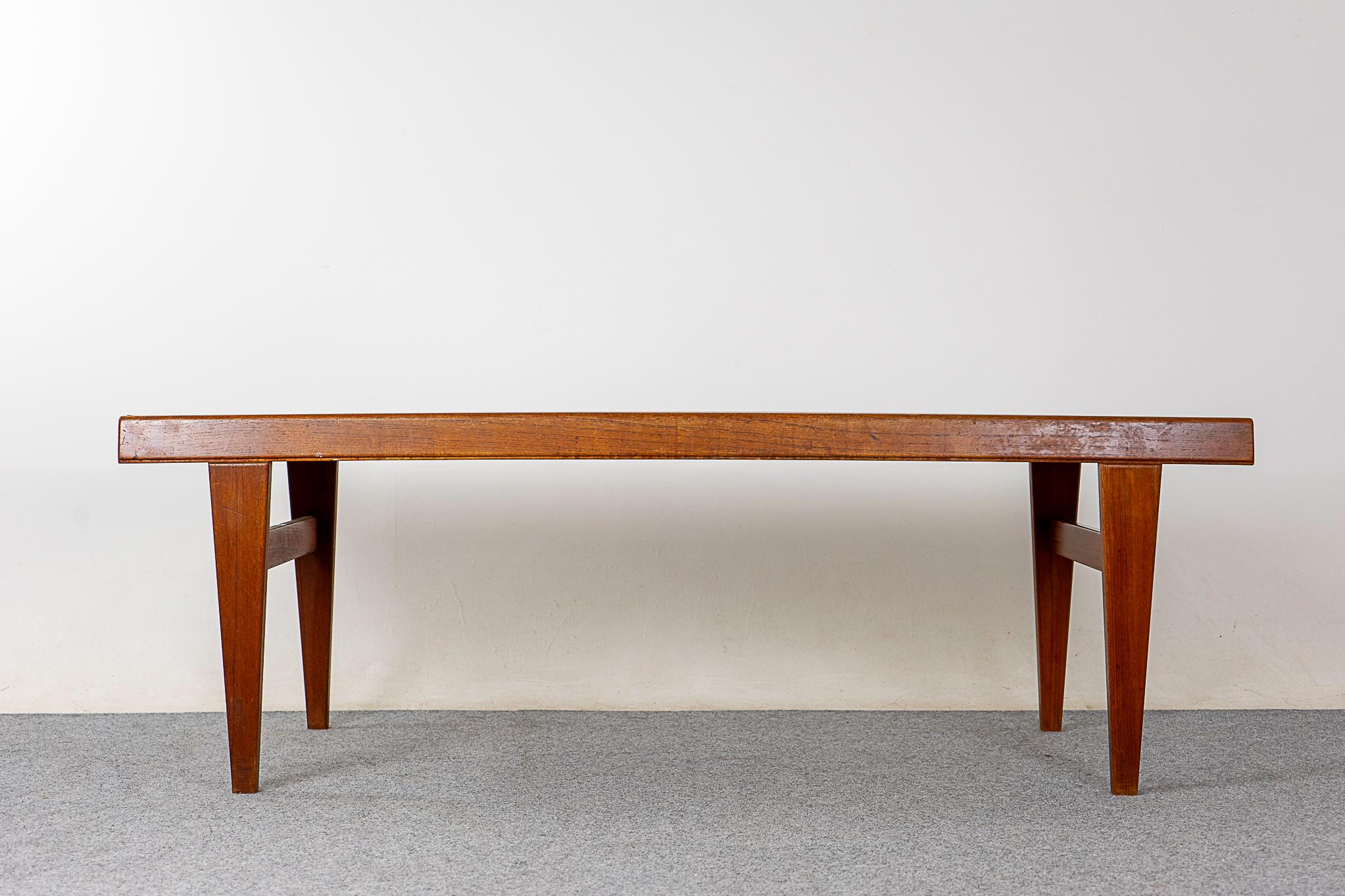 Teak mid-century coffee table, circa 1960's. Beautiful bookmatched veneer top, slender solid legs with cross supports. Pullout ends, a handy drawer on one side, a black melamine extension on the other! 

Unrestored item with option to purchase in