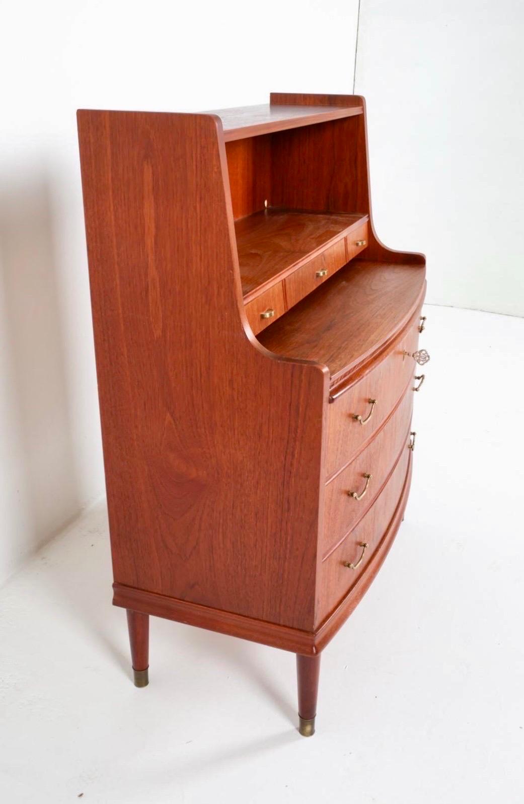 Stunning Danish Modern teak bow front chest/secretary desk over four drawers.  Key included and could be used as dry bar as well.  Original brass hardware and pulls.  When desk is pulled out, its width is 15.75