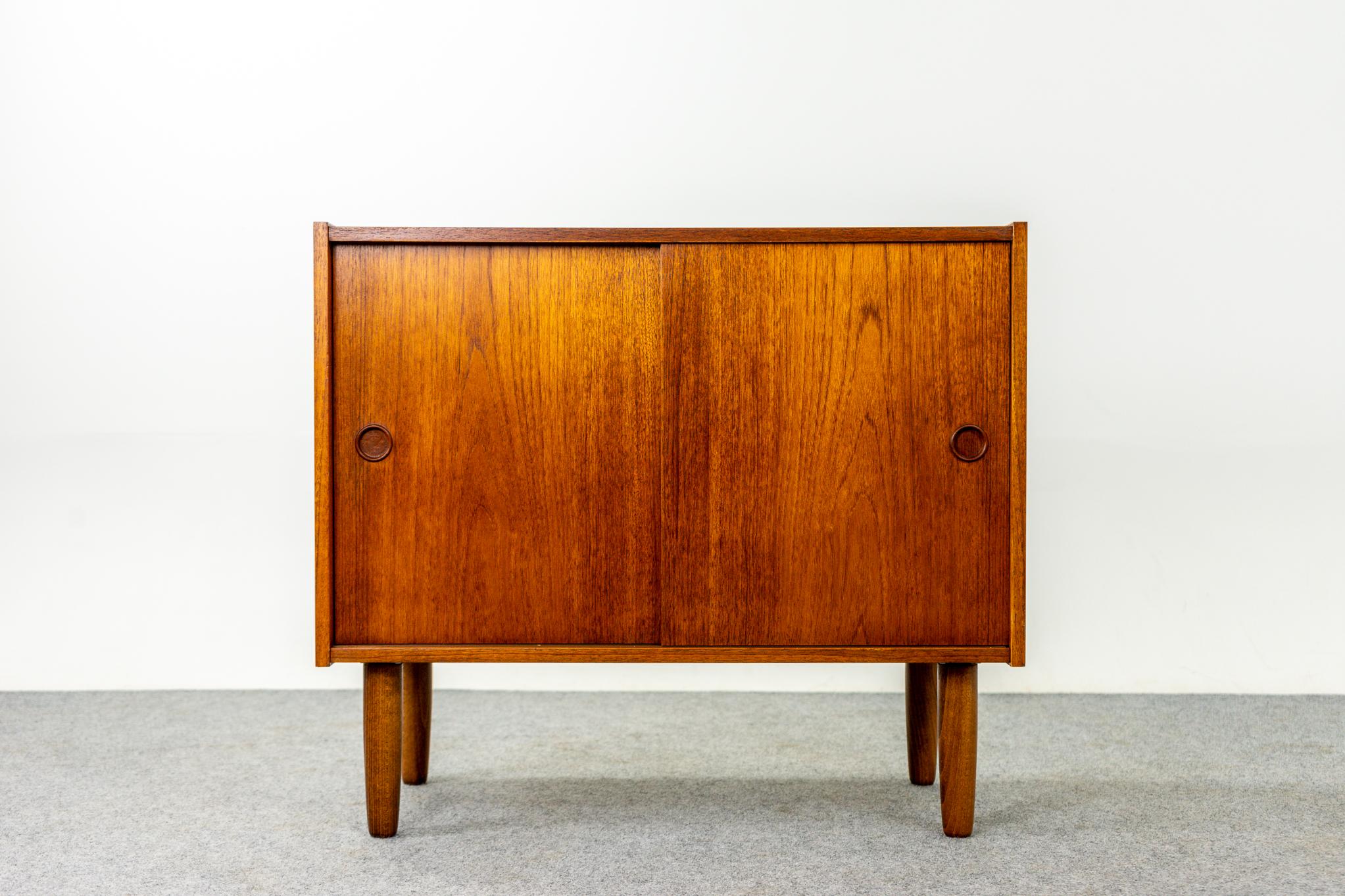 Teak cabinet, circa 1960's. Low profile cabinet with sweet circular pulls and adjustable centre shelf, the perfect condo sized storage solution. Solid tapering cylindrical legs. Great condition. 
Add the extra storage you've always needed.