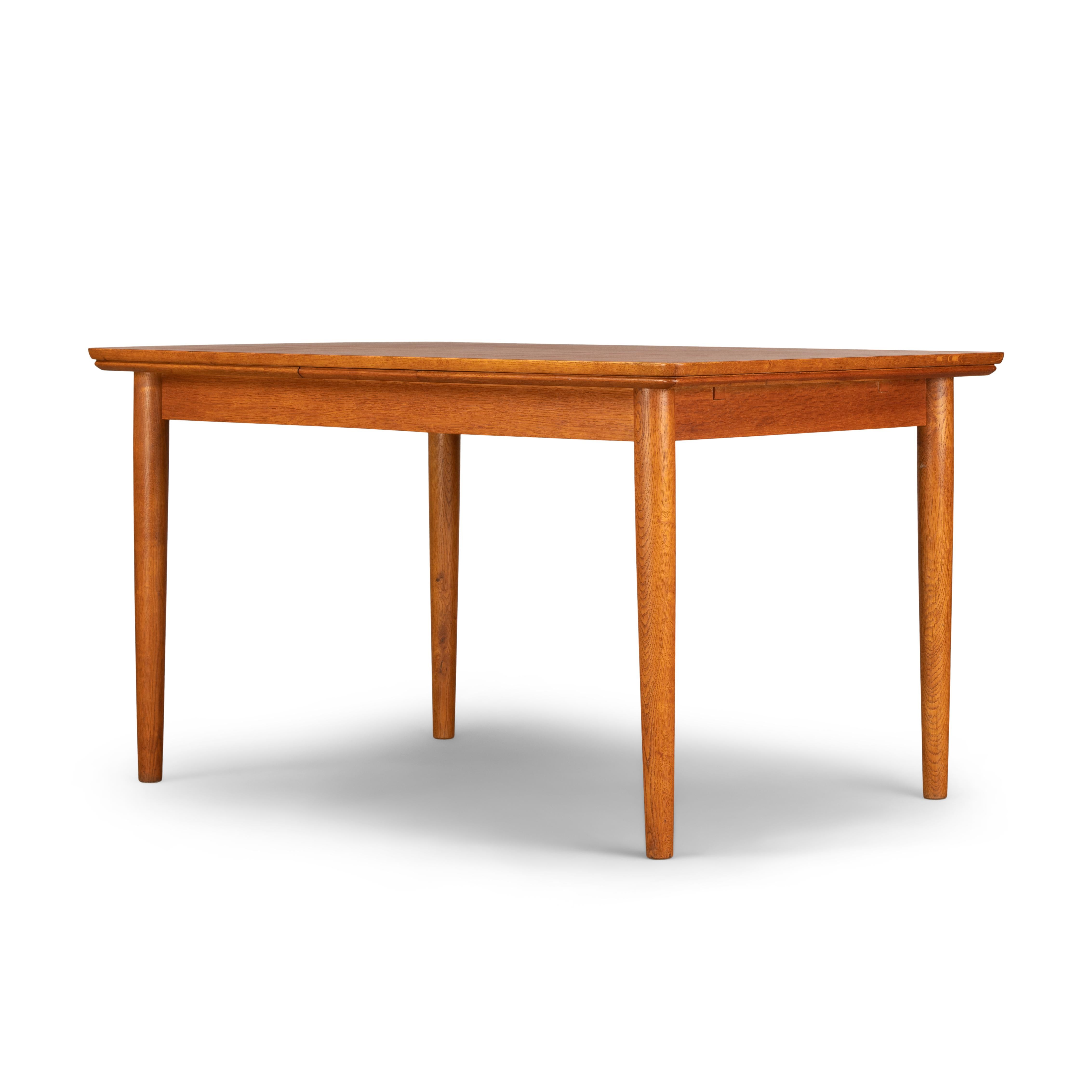 Cette table de salle à manger danoise a été fabriquée dans les années 1960. Elle est dotée de pieds en teck massif et de deux rallonges qui mesurent chacune 51 cm et permettent d'allonger la table jusqu'à 232 cm. Les rallonges sont cachées sous le