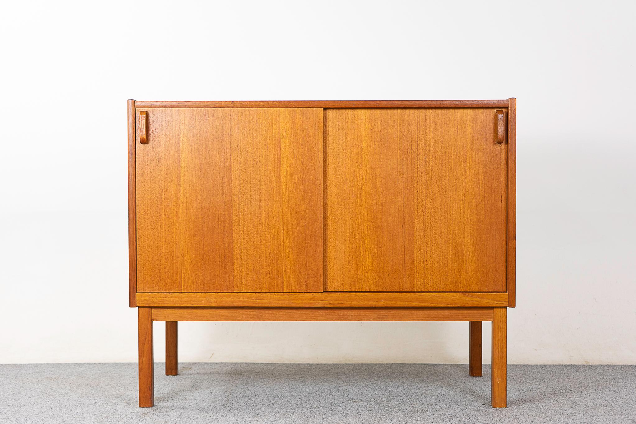 Teak mid-century cabinet, circa 1960's. Clean, simple lined design highlights the exceptional book-matched veneer throughout, removable shelf and interior drawer.