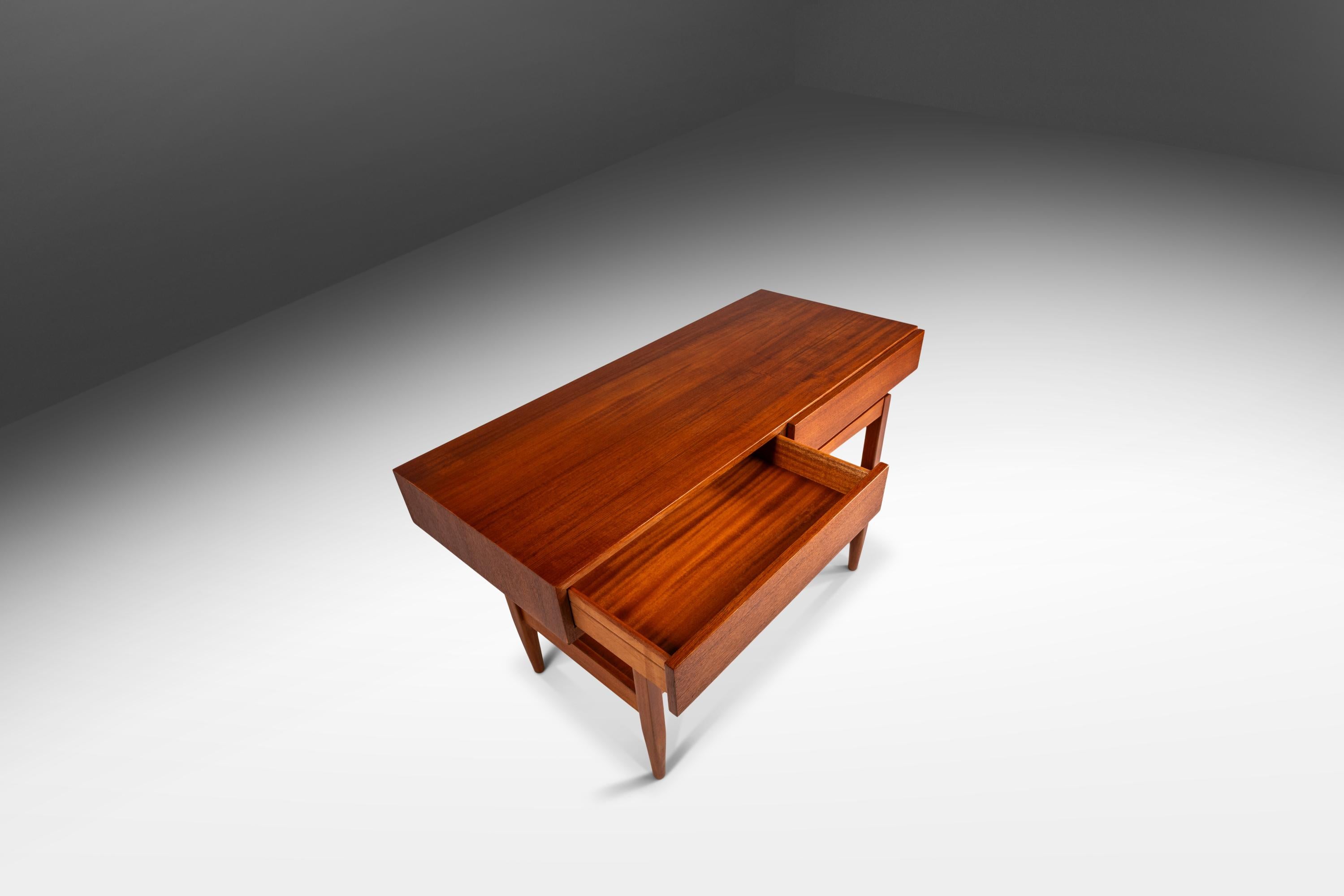 Introducing a true Danish Modern masterpiece: a rare teak console table designed by the incomparable Ib Kofod Larsen for Faarup Møbelfabrik. This iconic table has been fully restored and refinished making it the perfect addition to any modern home.