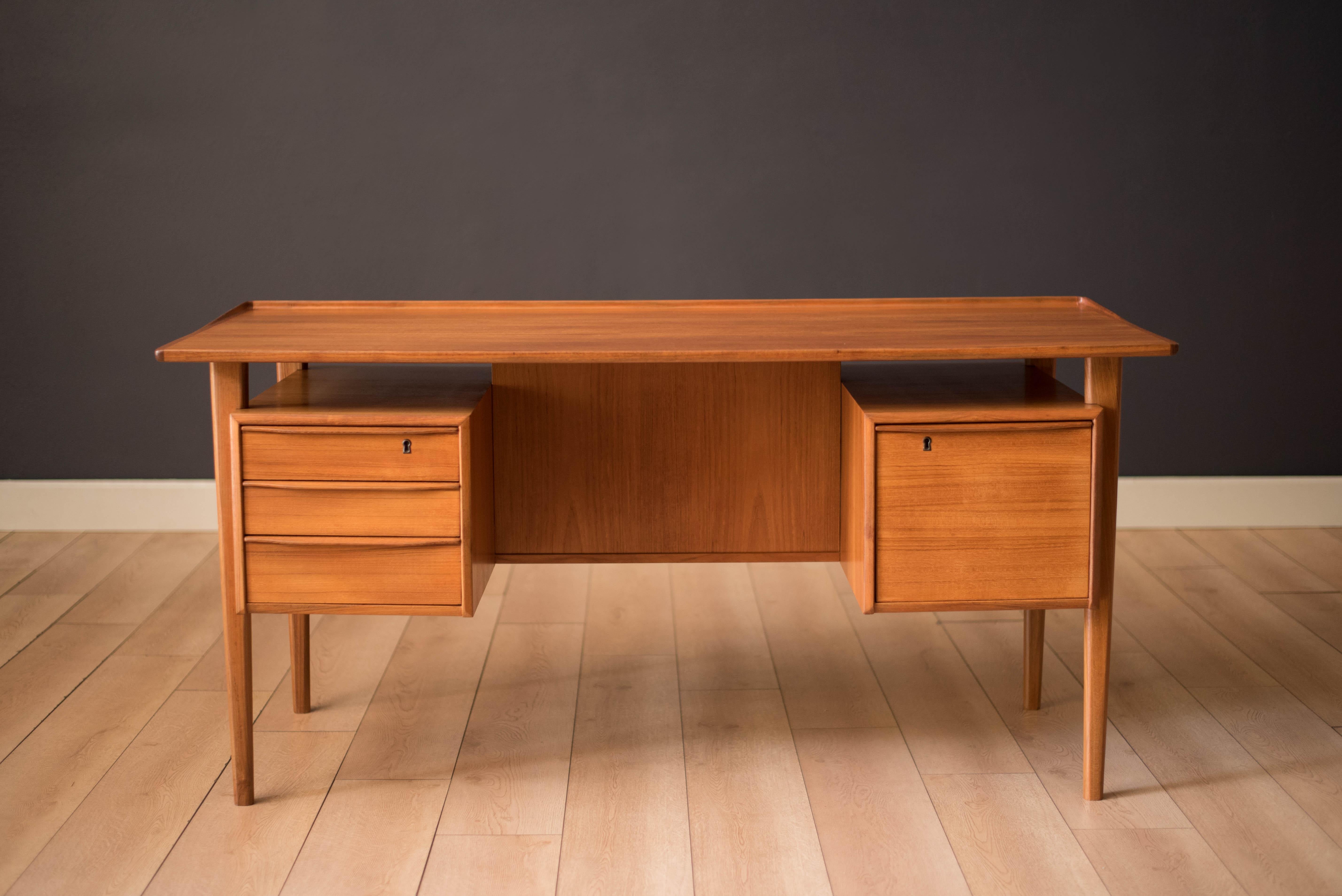 Mid-Century Modern Executive desk in teak designed by Peter Løvig Nielsen for Dansk. Features a unique floating top with a raised lip edge and external supporting legs. This piece includes three dovetailed drawers plus a file cabinet accented with