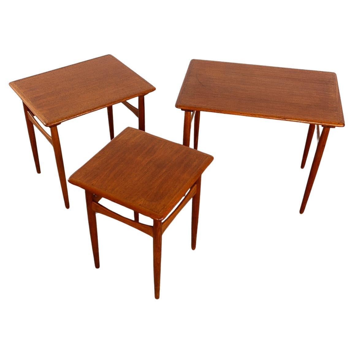 Teak nesting tables, circa 1960's. Space saving design, the footprint of 1 table with the functionality of 3! Tapered legs and bow crossbars make these unique! 

Unrestored item with option to purchase in restored condition for an additional $200