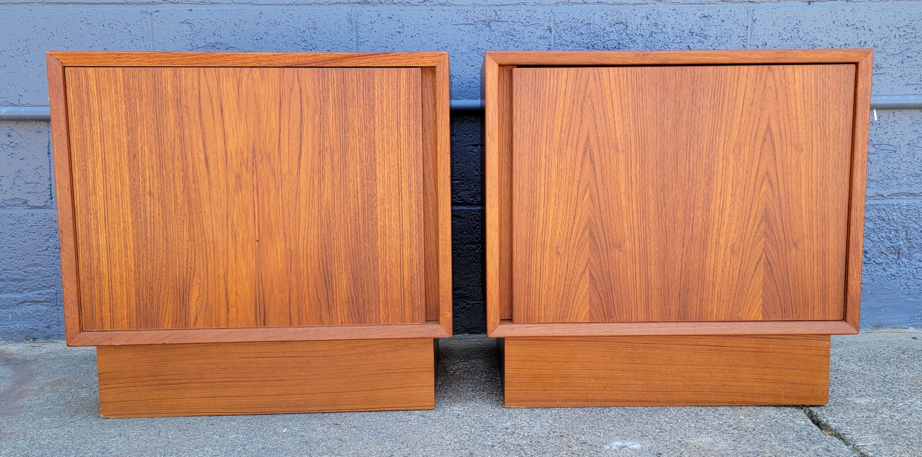 A pair of teak Danish Modern style nightstands or end tables. Each with single door to storage with one interior shelf. Very good condition with original finish.