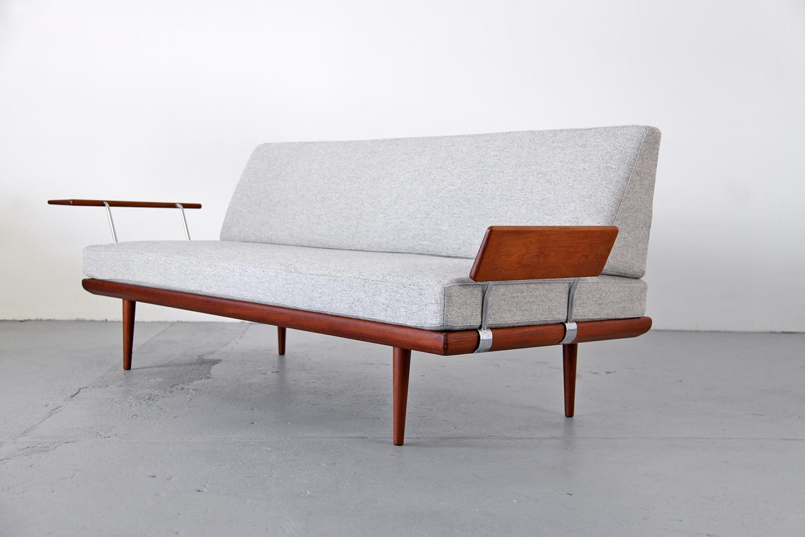 Lounge daybed made of teak wood. This is a very rare piece featuring two cushioned armrests, one of them an extremely rare edition. The piece has been covered with a new grey fabric 