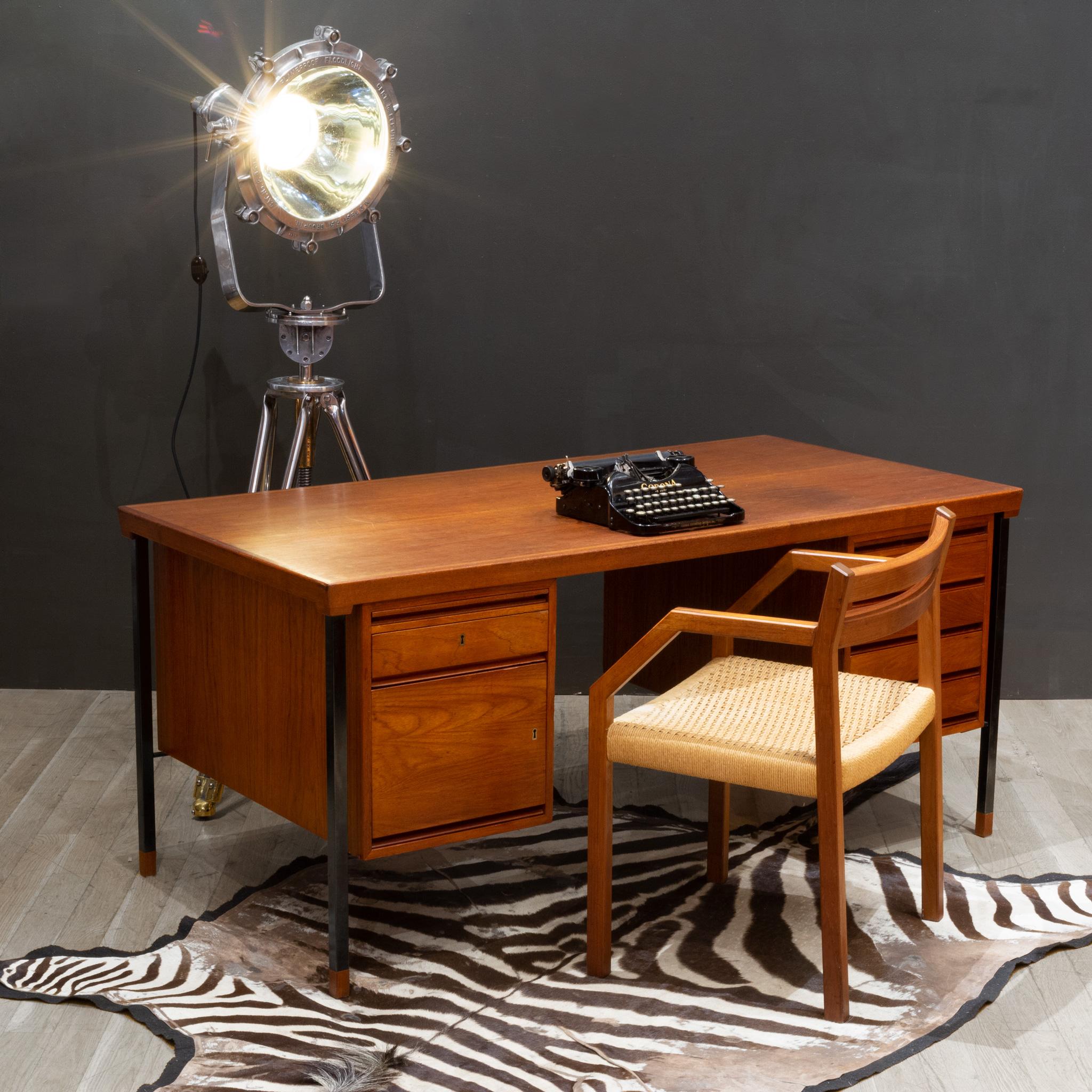 ABOUT

Mid-century modern Danish teak desk with black lacquered metal legs, five small drawers and one large drawer. Brass key holes on three drawers. Two pull out trays on either side lined with original green felt and topped with glass. Inset