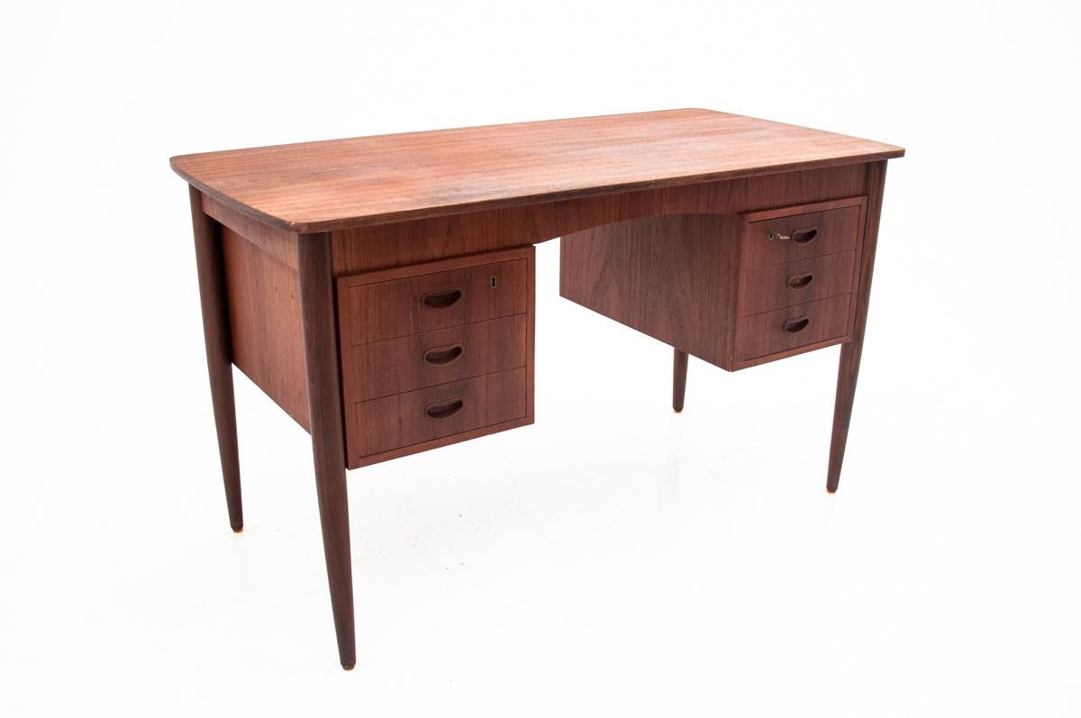 This stylish desk from Denmark from the 1970s has an unique shape. It is finished with a teak veneer. Front with six drawers. A key is included. On the back two shelves for books or other gadgets. It is maintained in very good condition. It has been