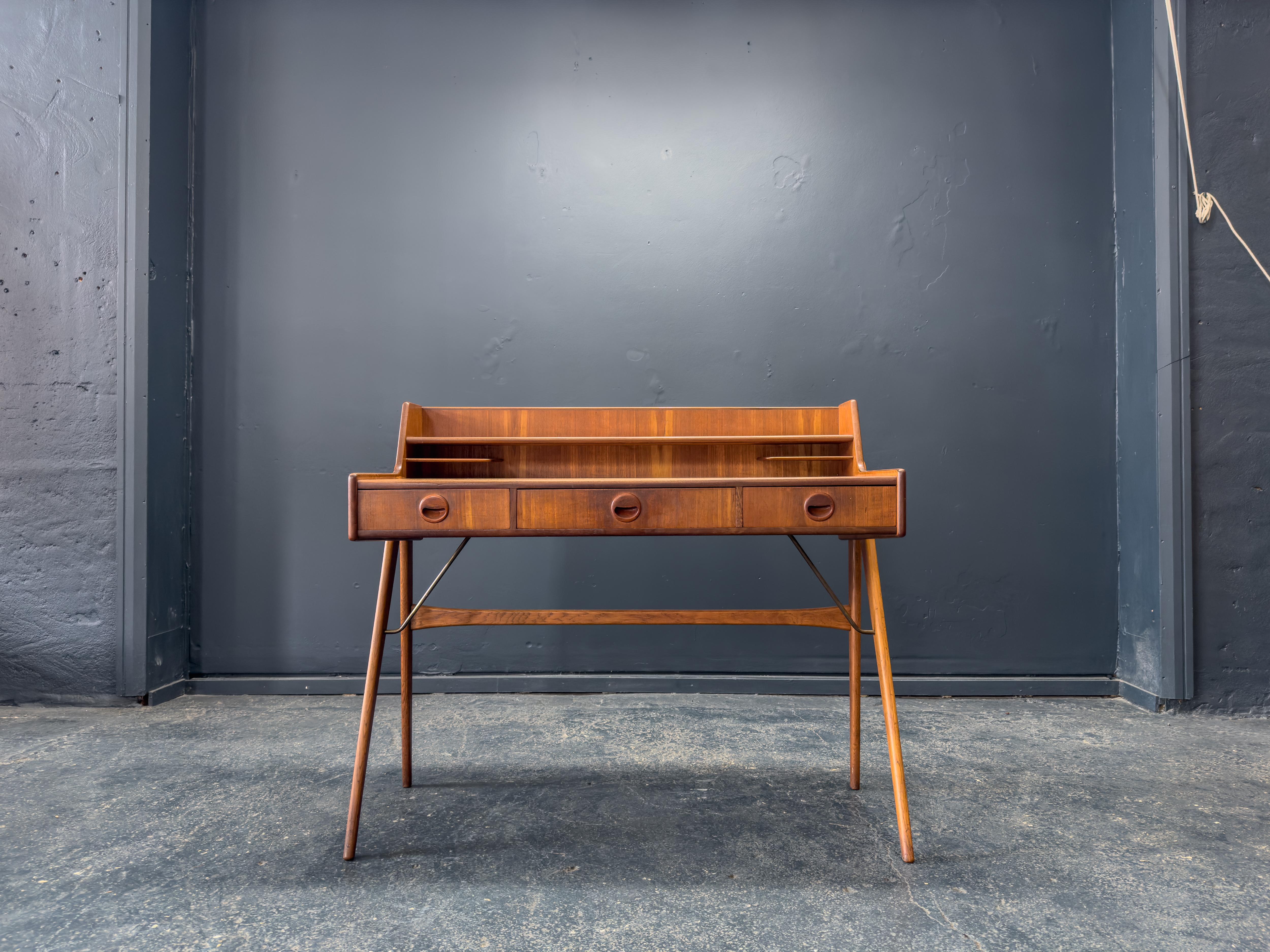 Questa straordinaria scrivania in teak è un pezzo di design di metà secolo estremamente espressivo, che si distingue per la sua forma architettonica e la sua leggerezza scultorea. Il design bilancia l'eleganza con la funzionalità, rendendolo