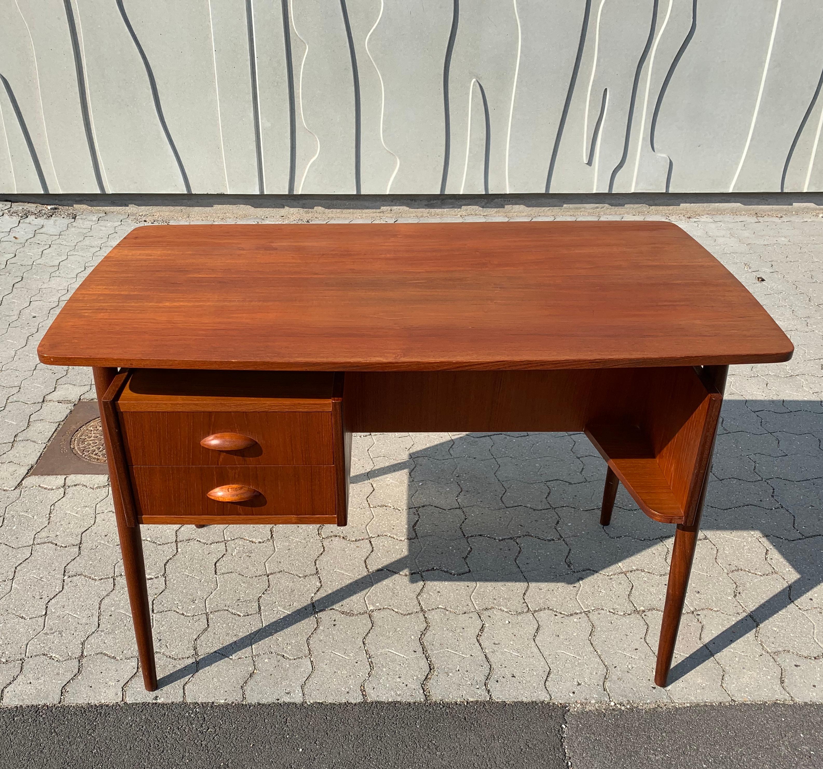Stunning Danish teak desk in the style of Gunnar Nielsen Tibergaard. Because of the design, the tabletop seems to float. In front, there is a drawer unit and a small shelf and a spacious bookshelf on the back. 

Measures: W 110 cm
D 59 cm
H 73