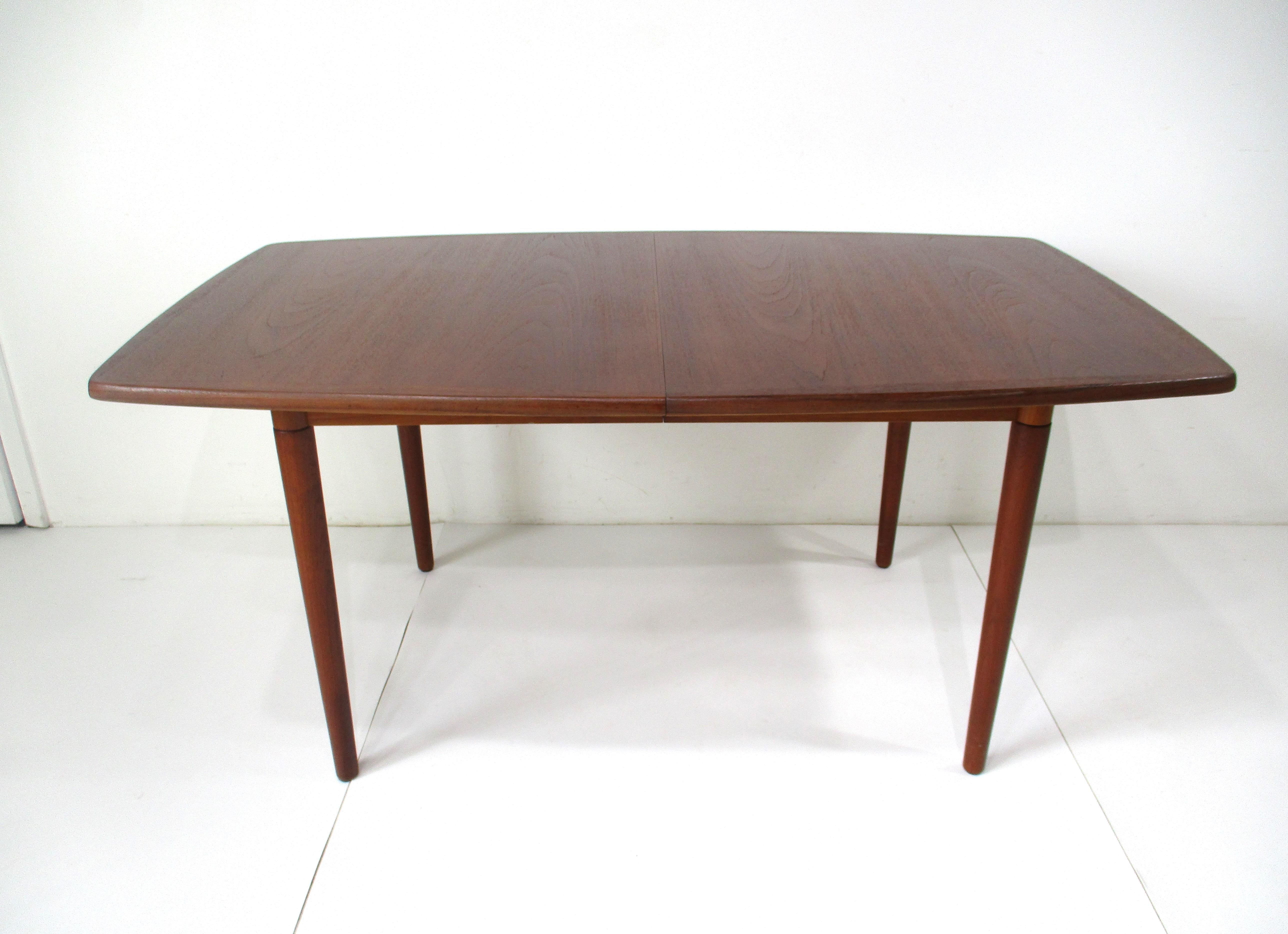 A darker teak wood dining table with nice rounded edges to the top and tapered legs having two 16.63