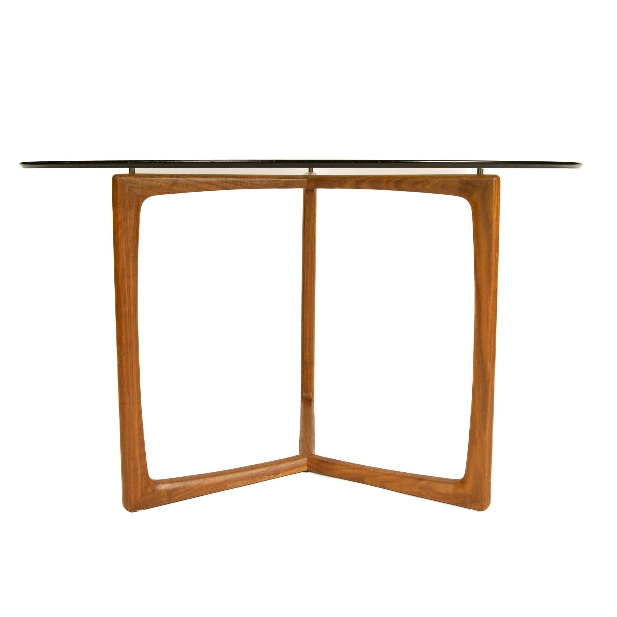 Une élégante base de table en teck avec un épais plateau en verre reposant sur des montants en laiton.