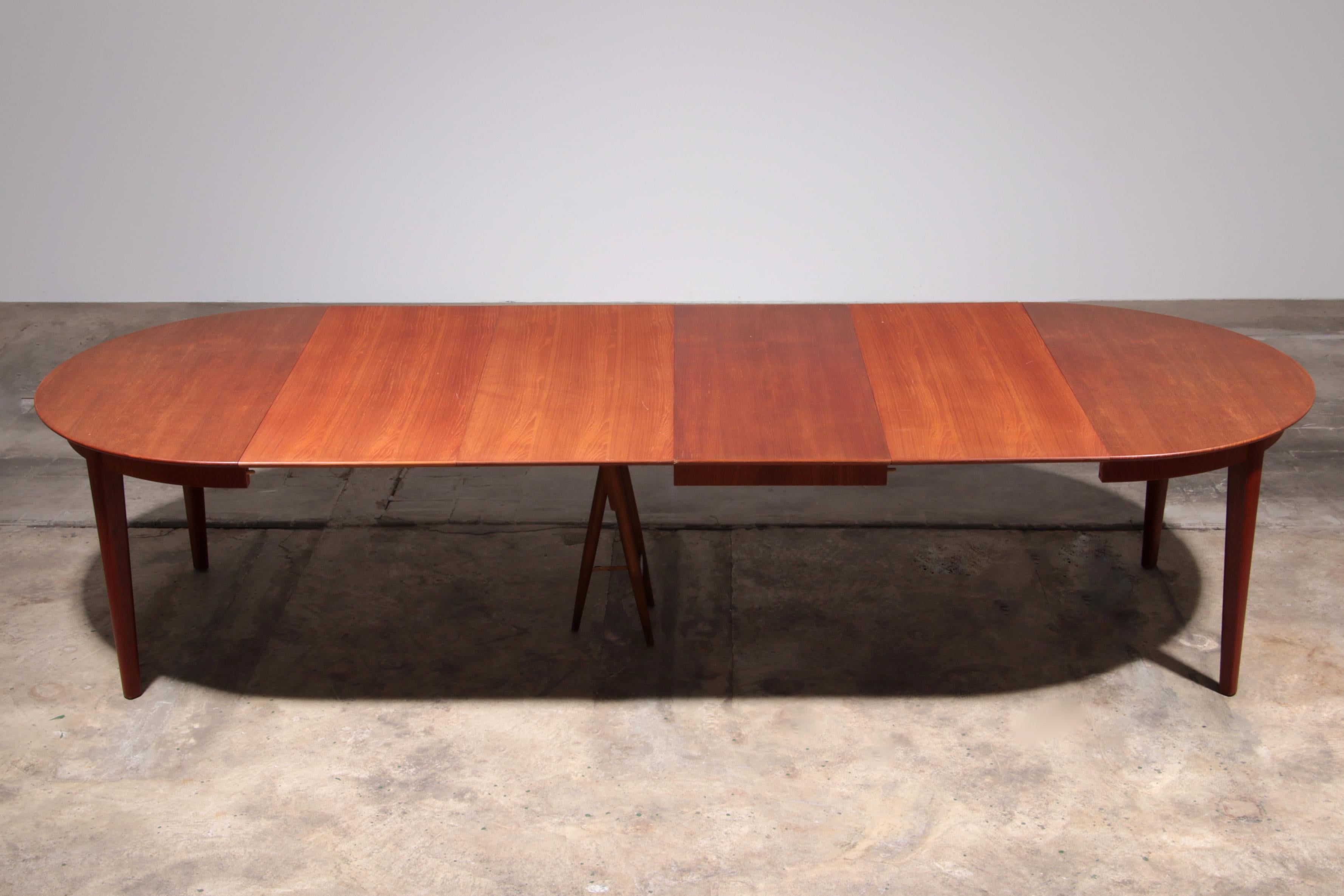This elegant teak dining table, designed by Henning Kjærnulf and produced by Sorø Møbelfabrik, offers both style and functionality. With a dark golden teak finish, the table includes four extension leaves, extending the length up to 325 cm. It