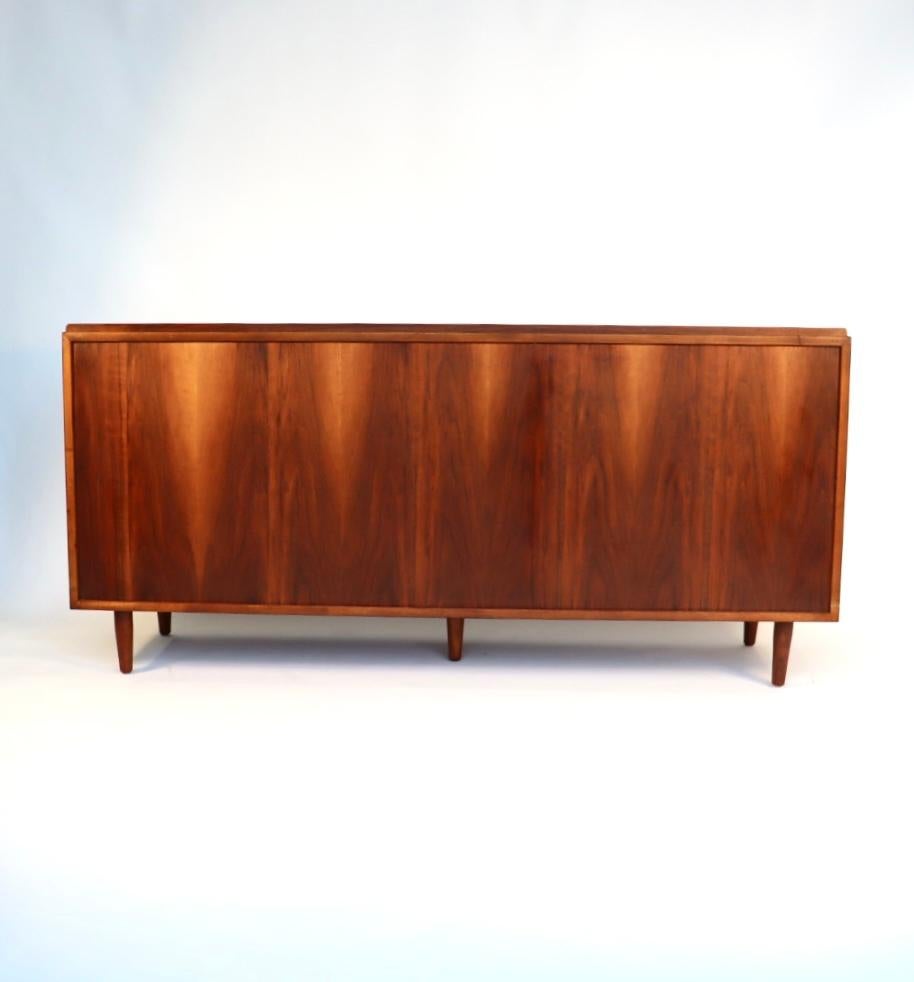 This incredible teak dresser is designed by Finn Juhl and has been fully restored. This is an incredible example of his work. The teak case is topped with a raised back-rail, three by three stacked drawers with black enamel brass pulls and it is