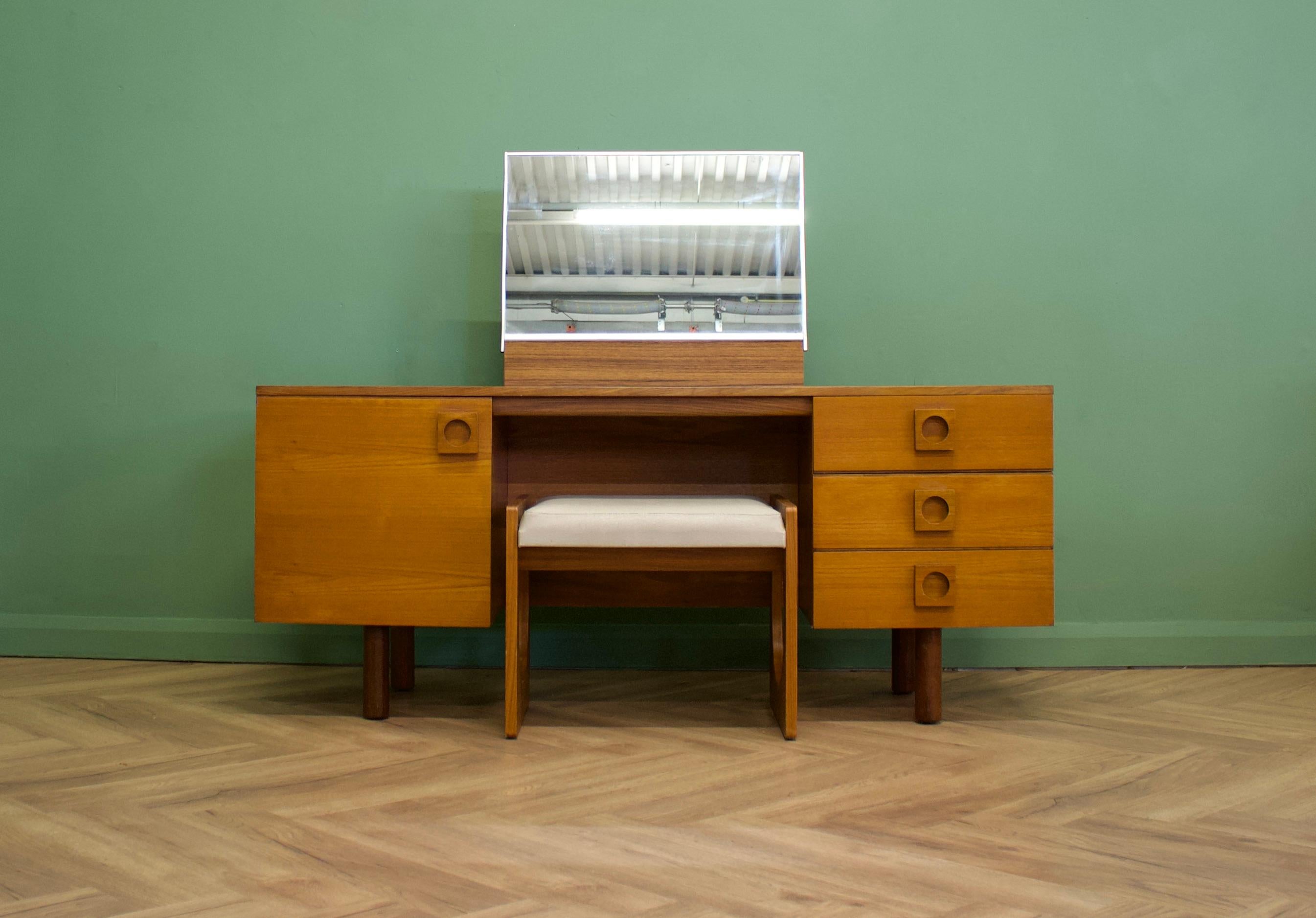 A midcentury teak dressing table & stool - from Uniflex

Made in the UK
There is one central mirror to this piece, a bank of three drawers and a cupboard, with an internal shelf - this shelf is fixed
The handles are made from solid teak, and