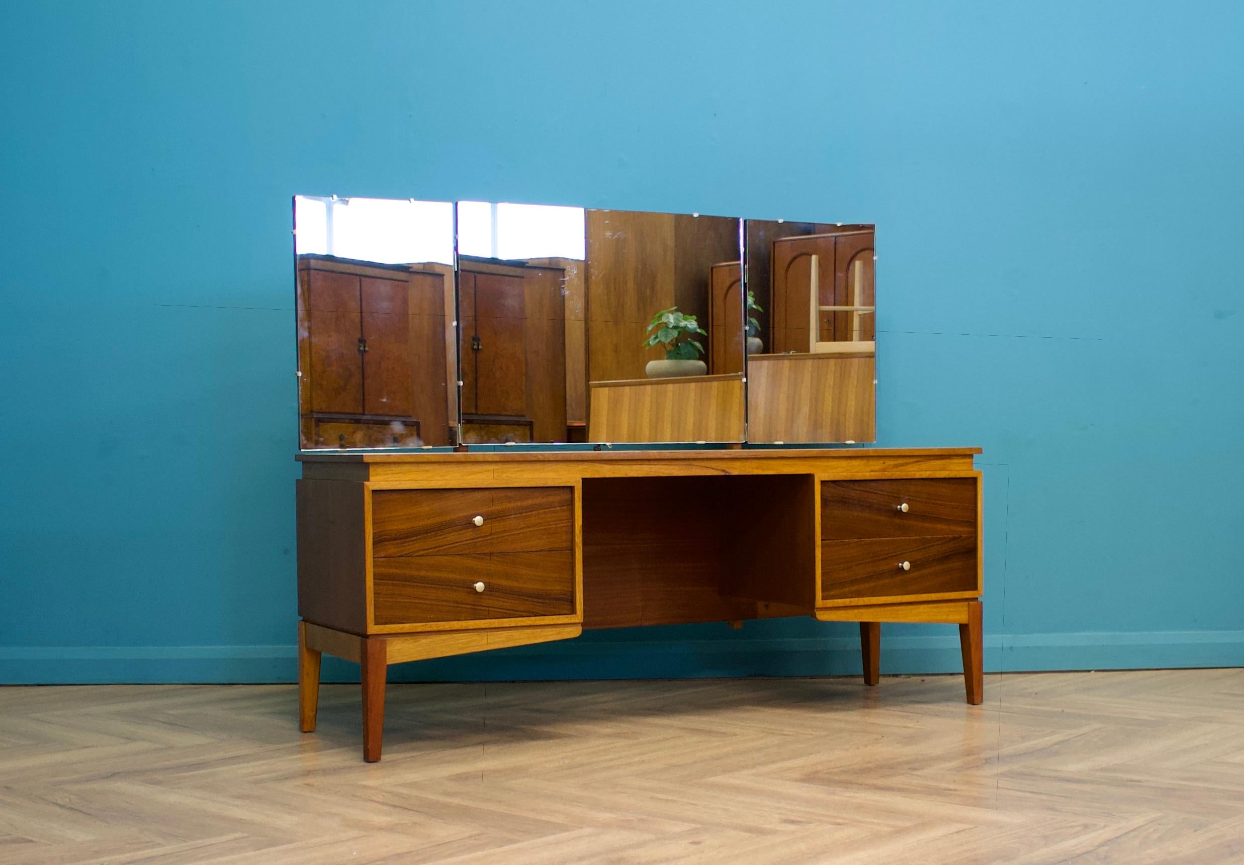 A mid century teak dressing table from Uniflex, circa 1960s

There's a triptych mirror, the middle tilts, the two sides swivel

Featuring four drawers each with a metal handle

Height to the top of the mirror is 120 cm