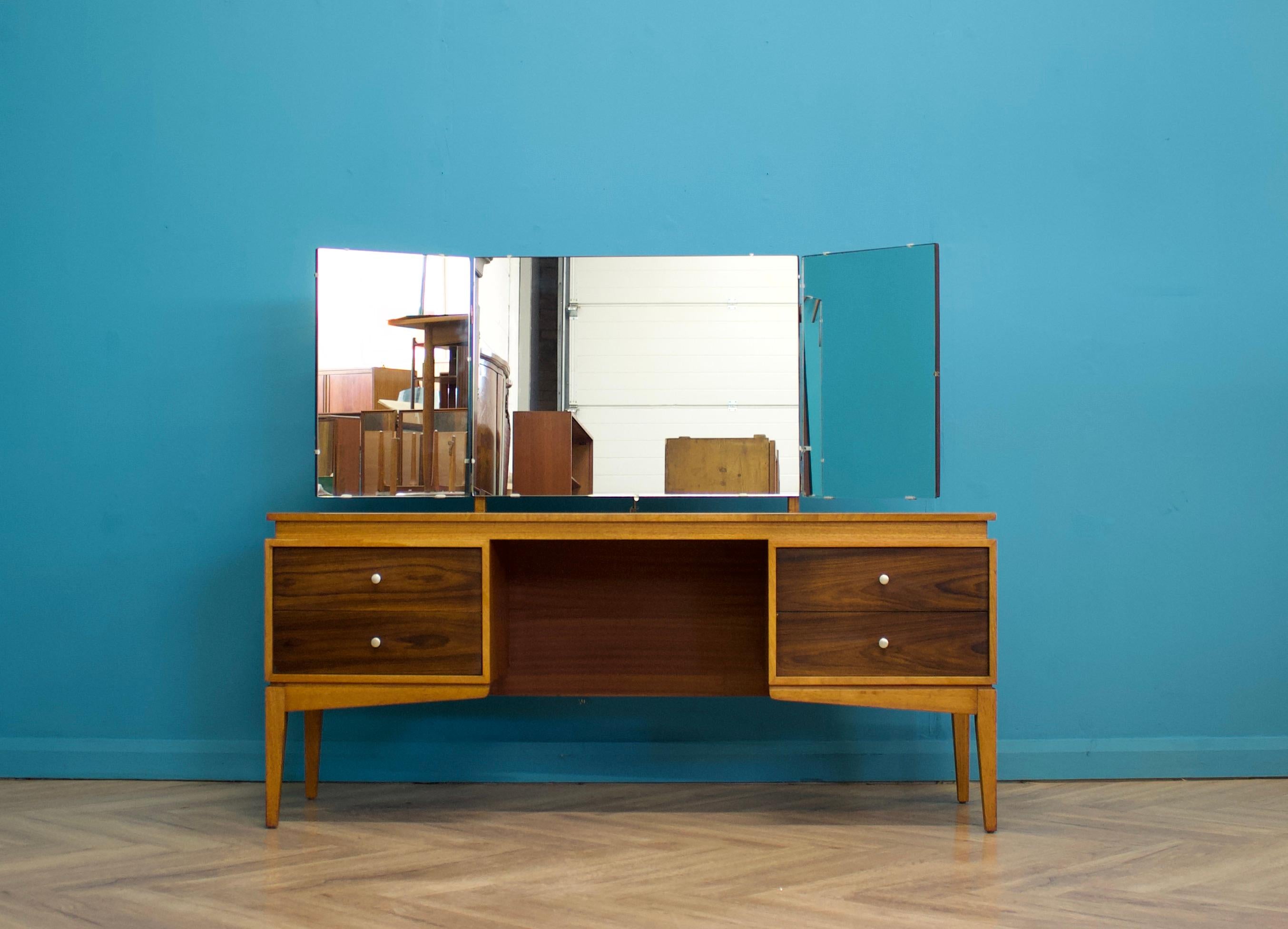 A mid century teak & walnut dressing table from Uniflex, circa 1960s


Featuring four drawersand a triptich mirror


Standing on tapered splayed legs


Height to the top of the mirror is 125 cm