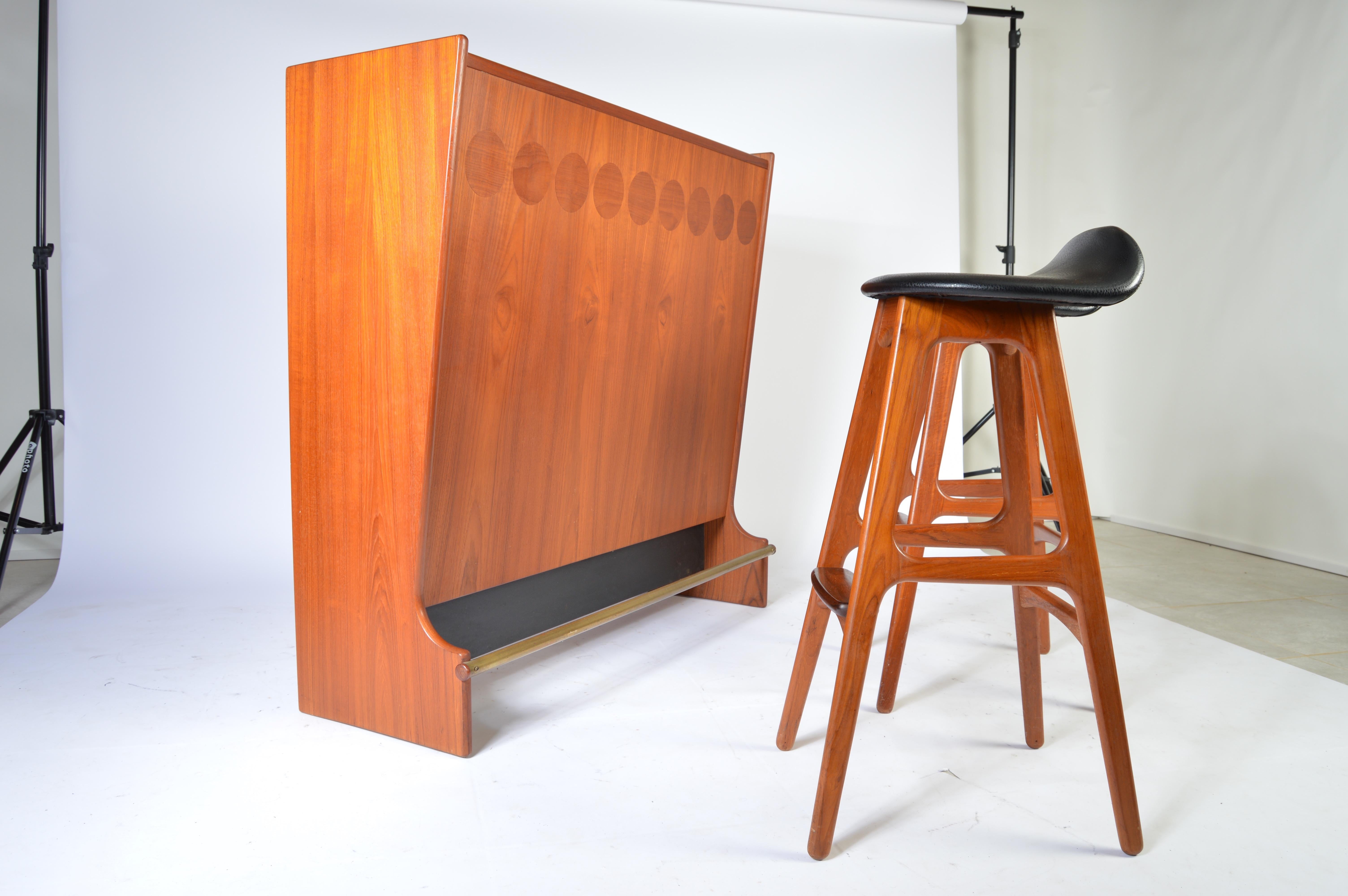 Teak dry bar designed by Johannes Andersen for Skanning and Son with two Erik Buch teak barstools having solid rosewood footrests. The bar features a brass foot rail with teak caps at both ends. Beautiful condition throughout,
circa 1960.

Bar
