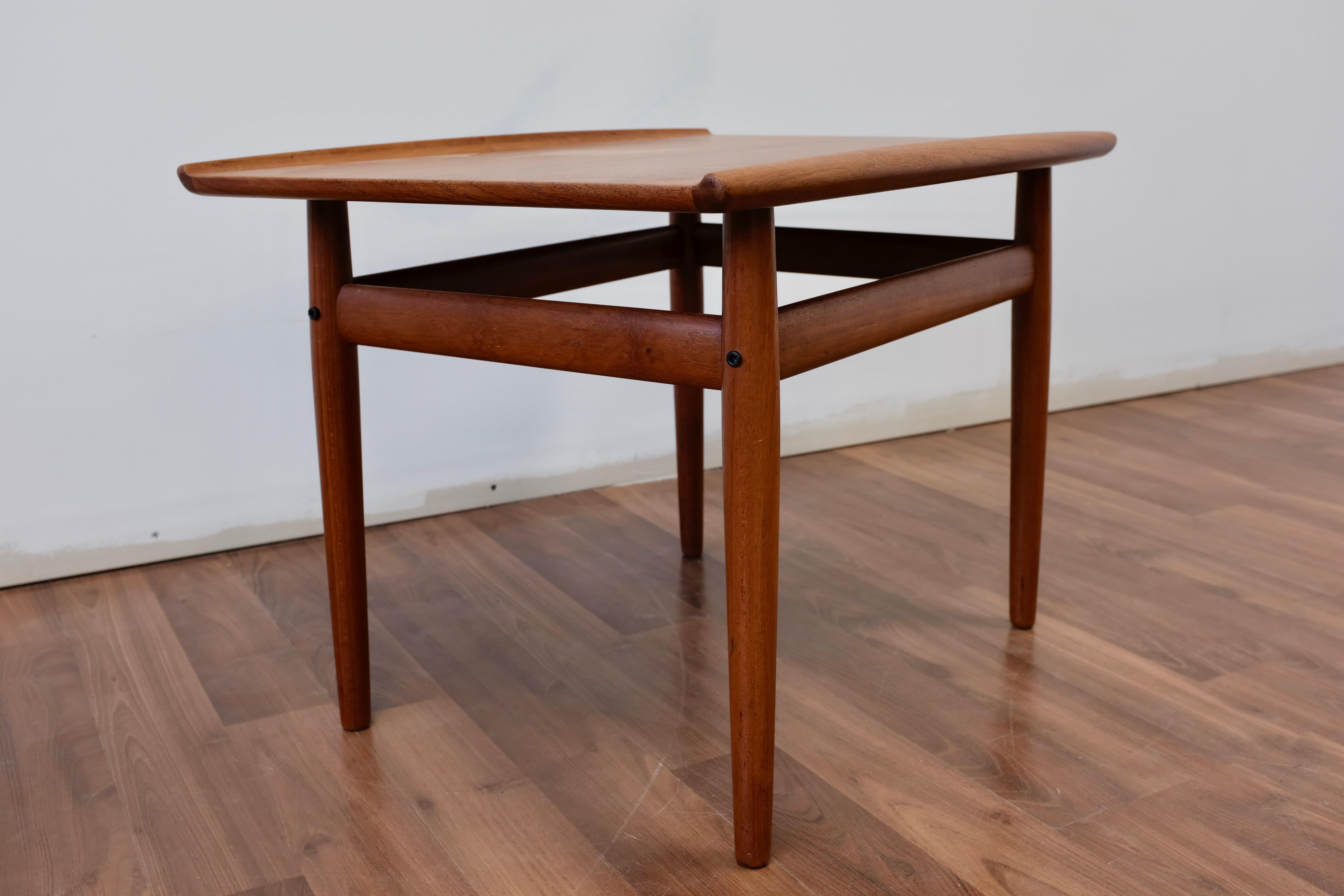 End table designed by Grete Jalk and made in Denmark by Glostrup Møbelfabrik.

Solid teak frame, teak veneered top with distinctive solid teak lipped edging. All joinery is solid and wood surfaces show minimal wear.