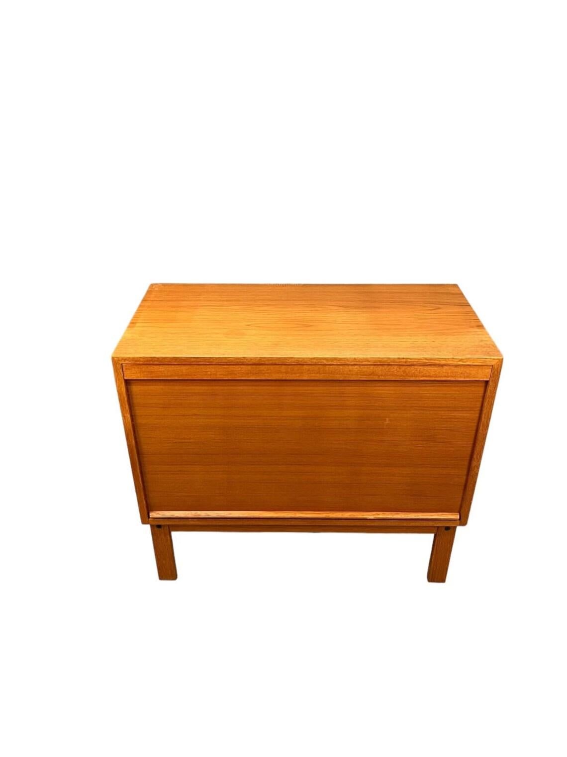 This mid-century modern teak cabinet from Denmark is a stylish and functional addition to any room. With a sliding door and (7) sliding drawers, it is perfect for storing files, books, or any other household item. The cabinet is made of high-quality