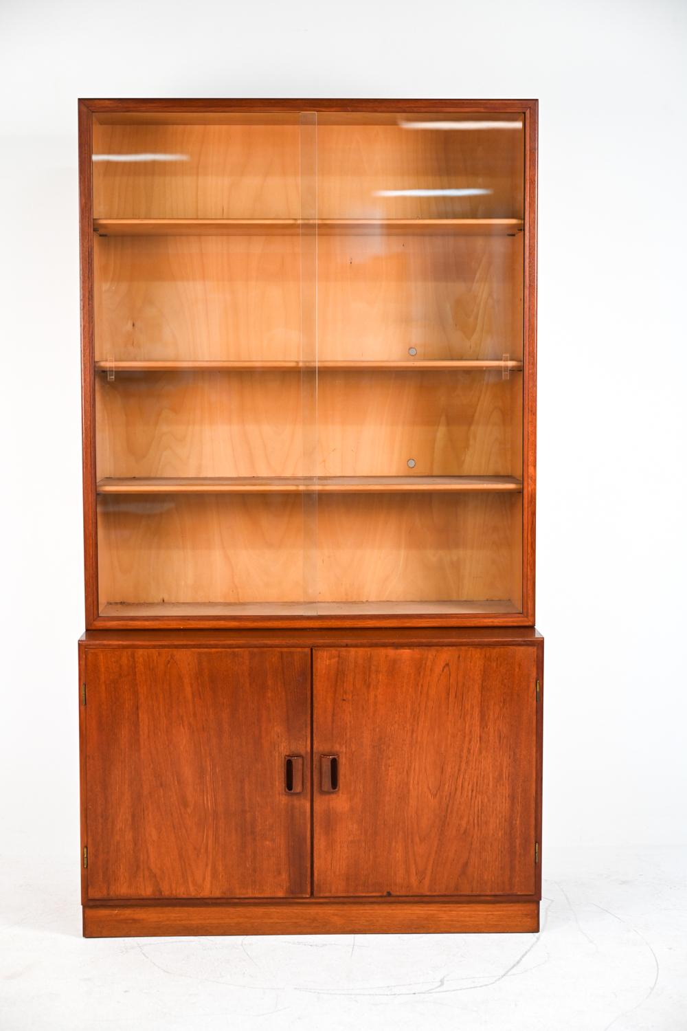 A fabulous high quality two-piece Danish mid-century bookcase display cabinet in teak wood, designed by Børge Mogensen for the Danish manufacturer Søborg Møbler. This cabinet features adjustable shelves behind sliding glass doors and a bottom